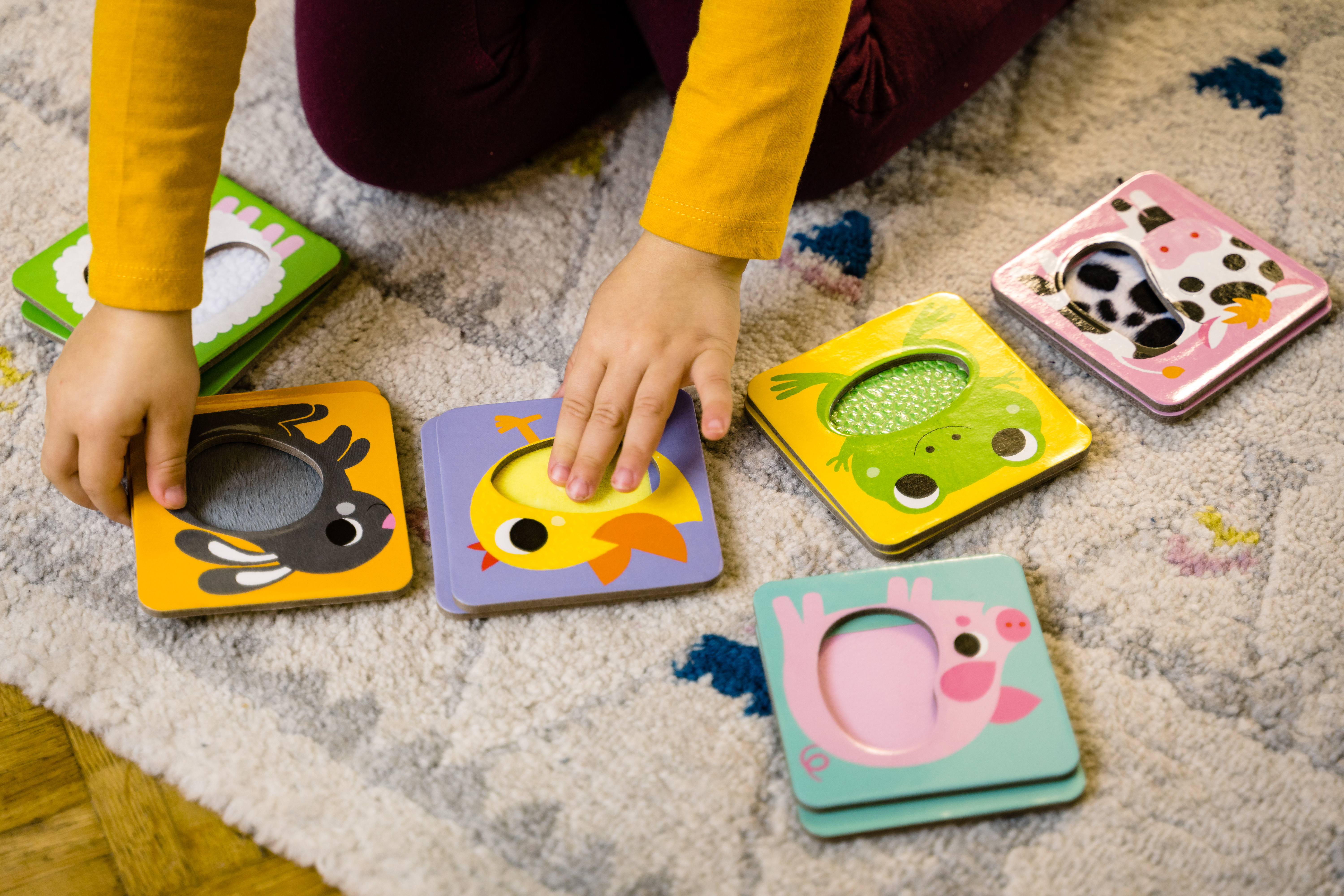 Kind spielt mit Puzzleteilen mit Tieren. Eine Kuh, ein Kaninchen und ein Küken sind sichtbar.