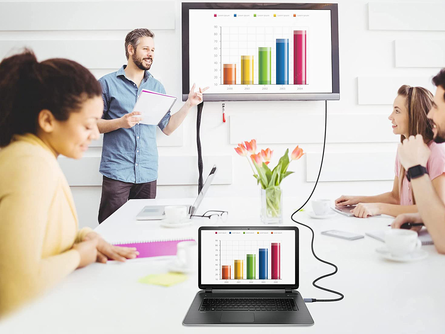 Ein Mann präsentiert Kollegen eine Grafik. Ein Laptop zeigt dieselbe Grafik.