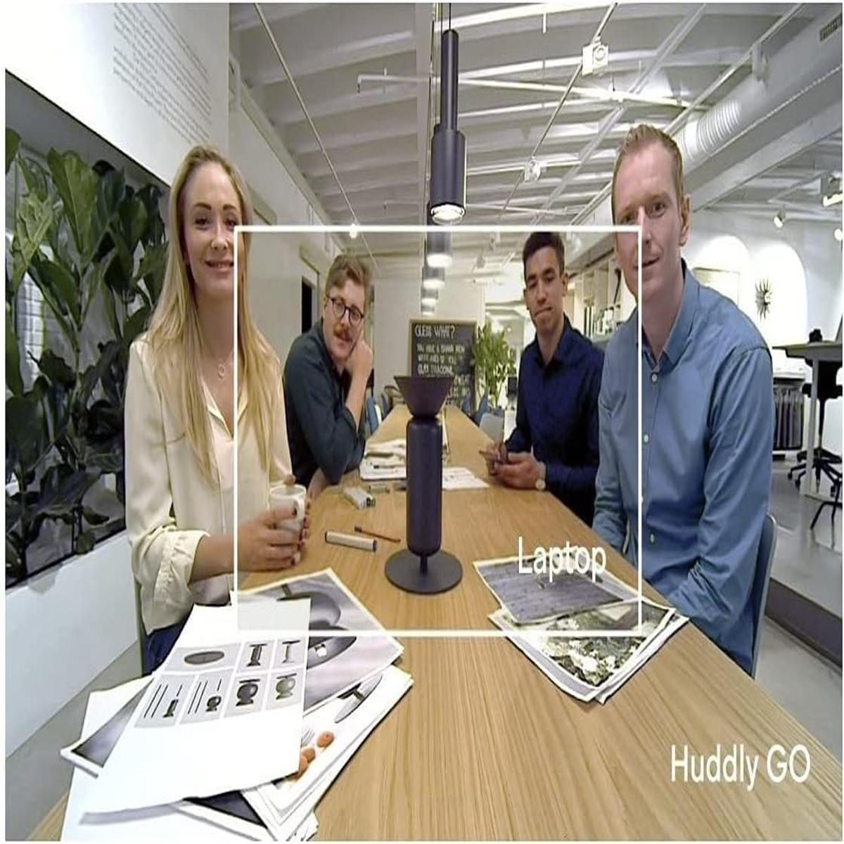 Quattro persone sedute attorno a un tavolo con carte e un laptop, etichettato 'Huddly GO'.