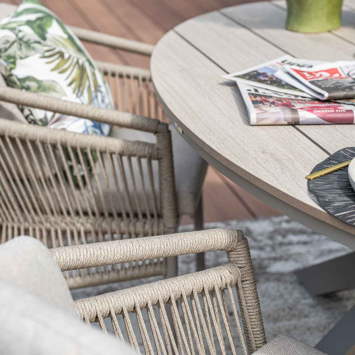 Een tafelsetting met een ronde houten tafel, tijdschriften, een bord en een stoel.
