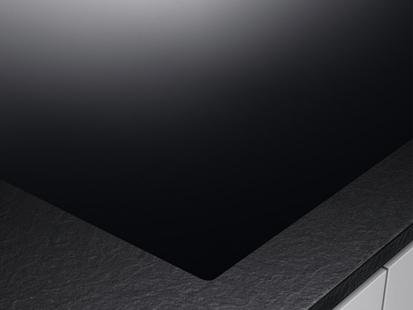 Una superficie del piano cottura nera, che mostra il design elegante e moderno dell'elettrodomestico da cucina.
