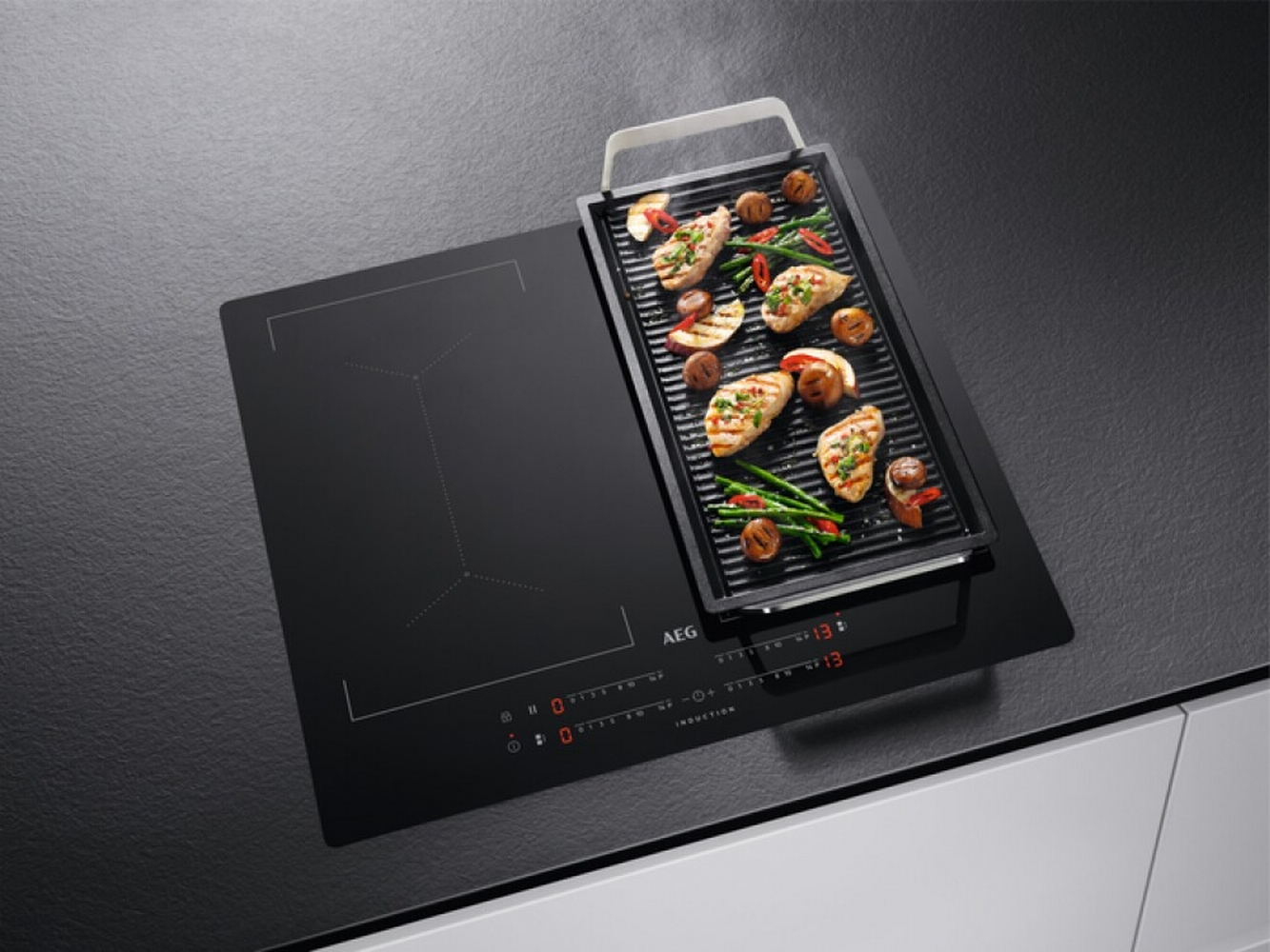 Un piano cottura a induzione con accessorio grill, con cibo cotto.