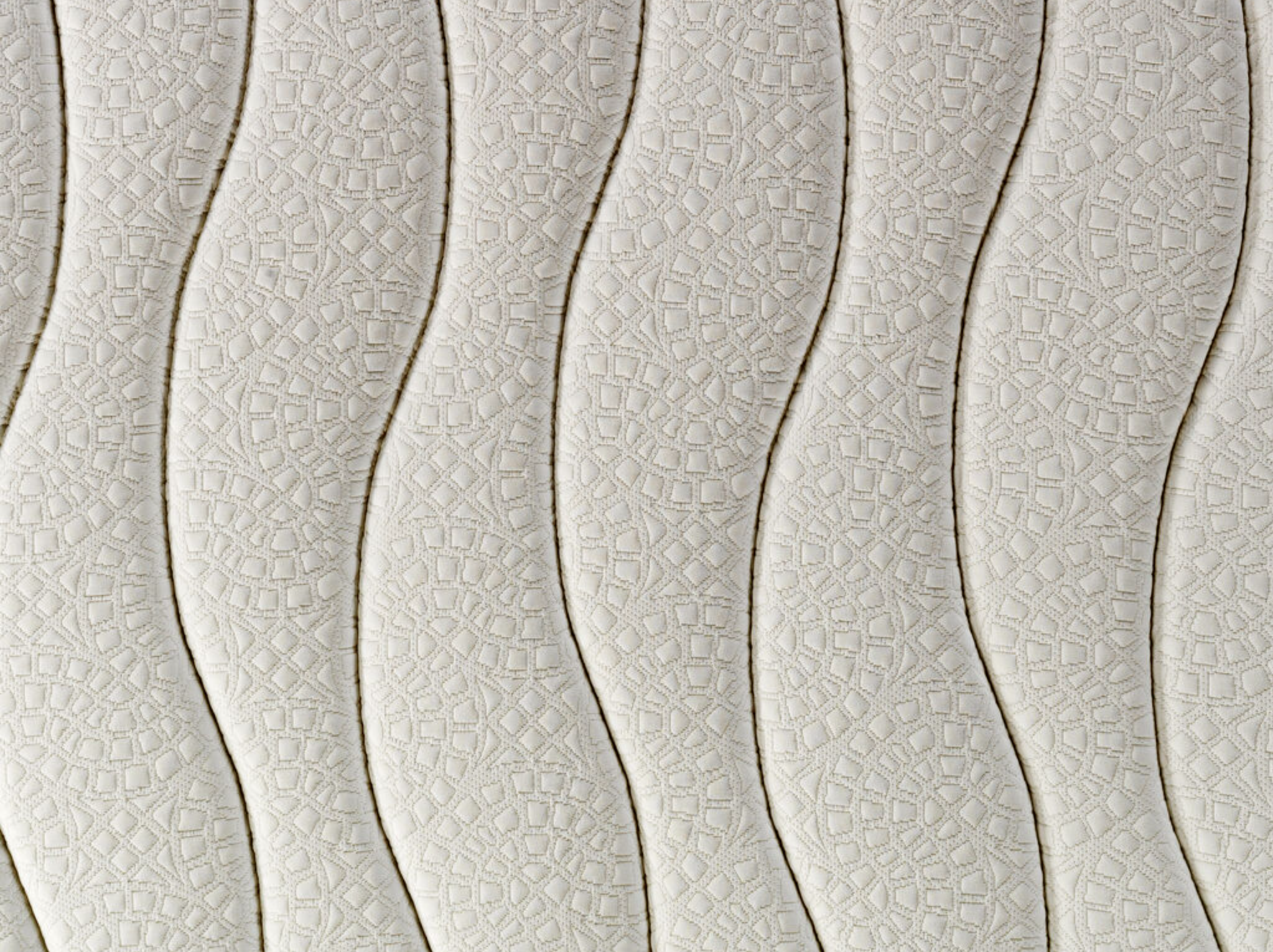 Primer plano de un colchón blanco con un patrón ondulado. El patrón está hecho de pequeñas formas geométricas.