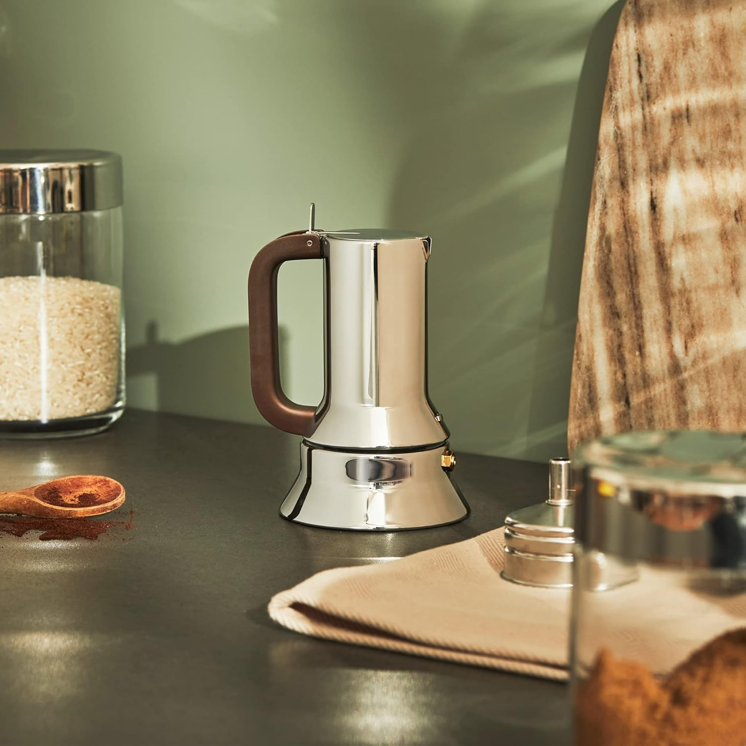 Ekspres do kawy ze stali nierdzewnej z drewnianym uchwytem, na blacie z przyprawami.