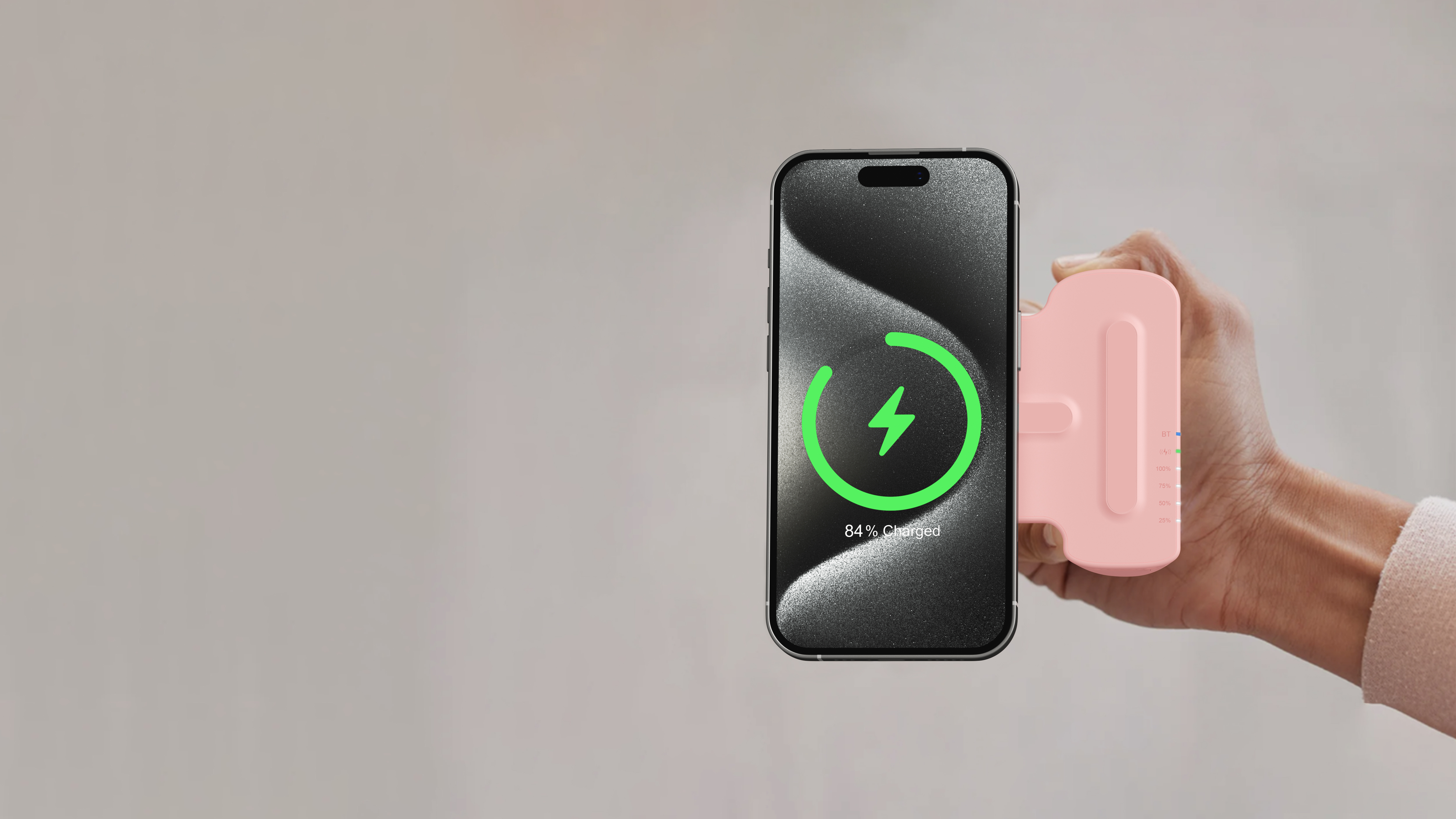 Un dispositivo di ricarica rosa collegato a un telefono che mostra un simbolo di ricarica. Il telefono mostra l'84% di carica.
