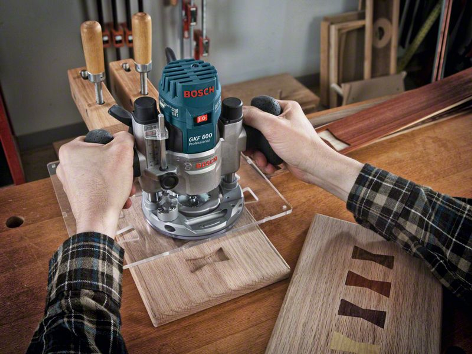 Eine Person, die eine Bosch GKF 600 Fräse für ein Holzprojekt verwendet. Eine Holzfliege ist sichtbar.