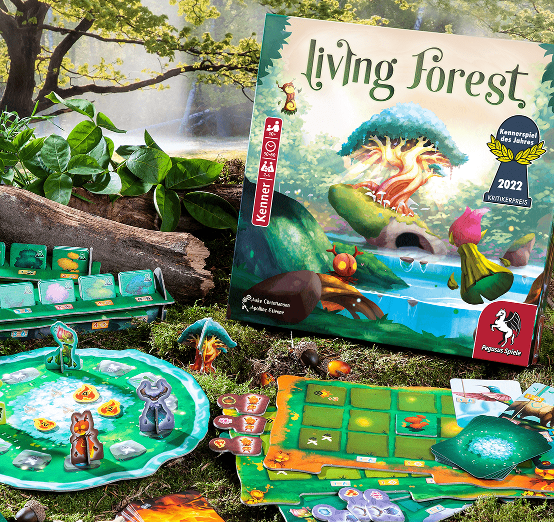Brettspiel Living Forest mit Komponenten auf einer grasbewachsenen Oberfläche, mit einer Box im Hintergrund.
