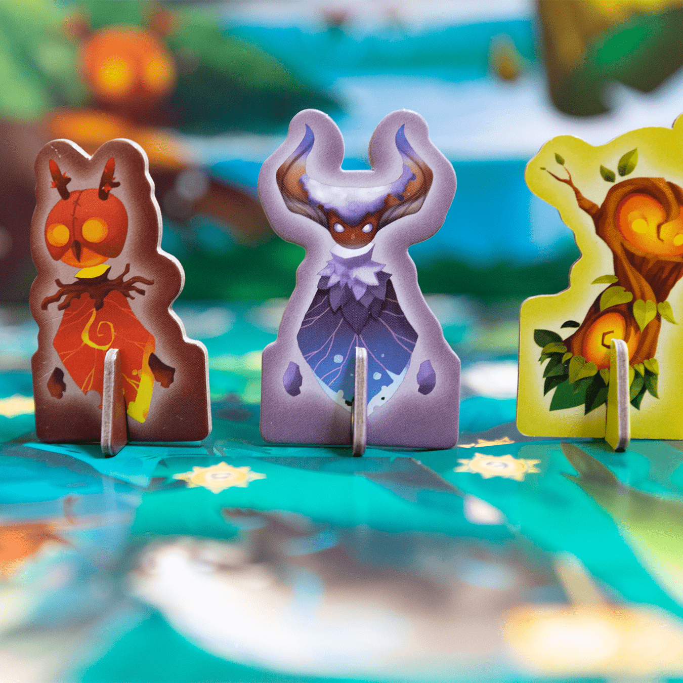 Nahaufnahme von Spielsteinen auf einem Spielbrett. Drei Charakter-Token sind im Fokus. Das Spielbrett ist grün.