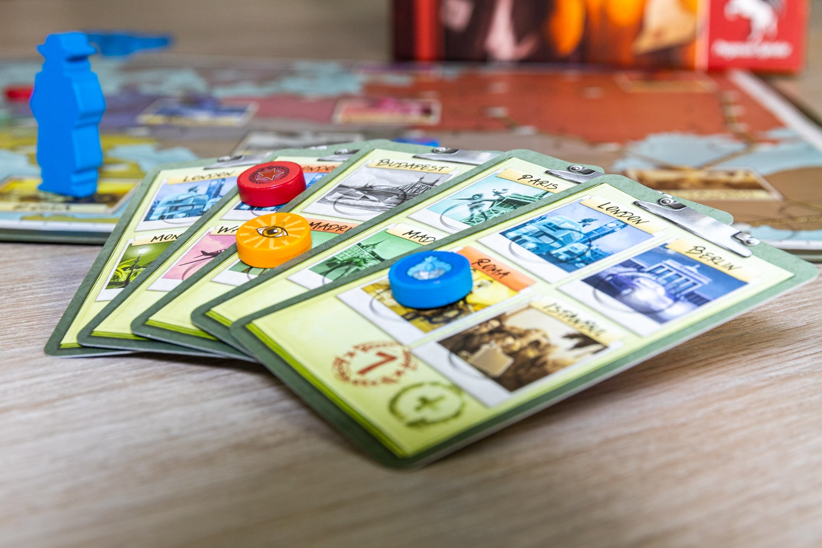 Nahaufnahme von Spielkarten, mit Spielsteinen und Spielfiguren auf einem Holztisch.