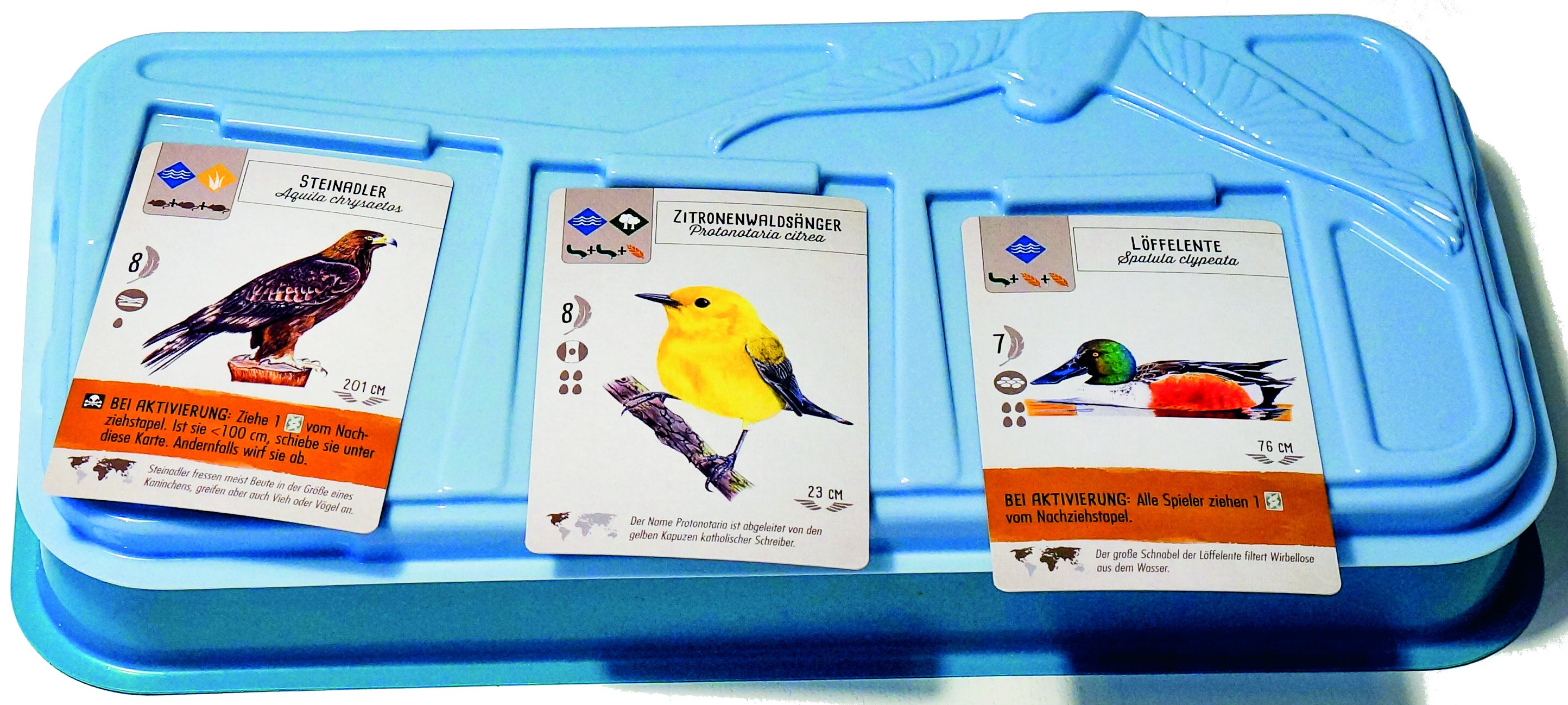Vassoio blu con carte. Le carte presentano illustrazioni di uccelli con informazioni e statistiche.