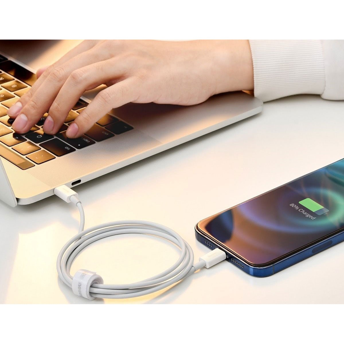 Laptop jest podłączony do telefonu białym kablem ładującym. Telefon pokazuje 89% naładowania.