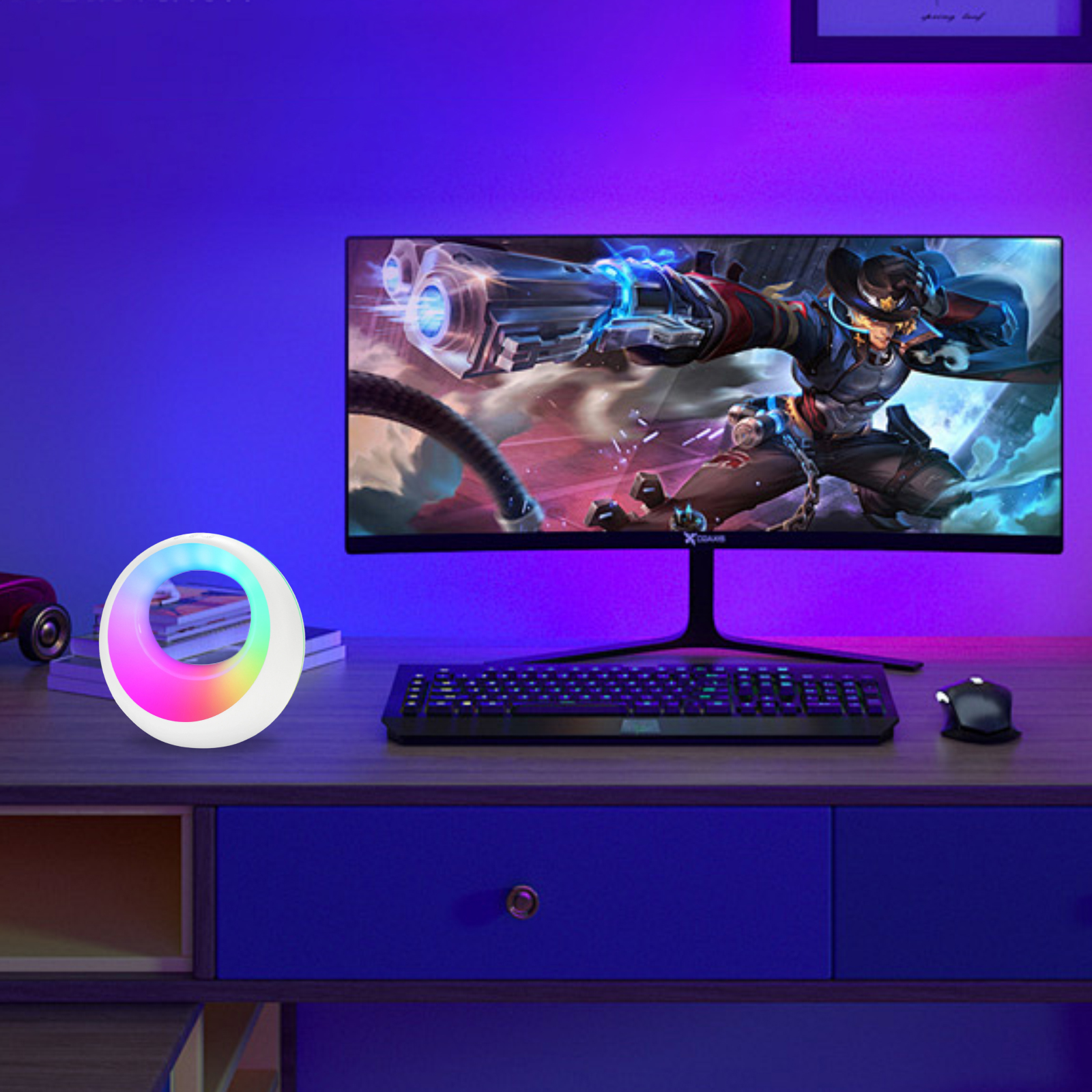 Ein farbwechselndes Ringlicht auf einem Schreibtisch neben einem Monitor und einer Tastatur.
