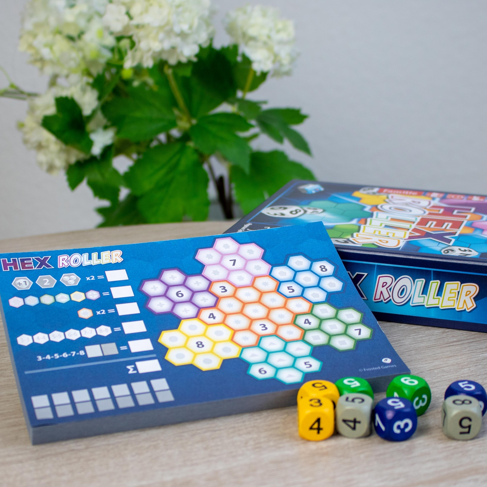 Nahaufnahme eines Brettspiels mit Würfeln, Karten und Spielbrettteilen auf einem Holztisch.