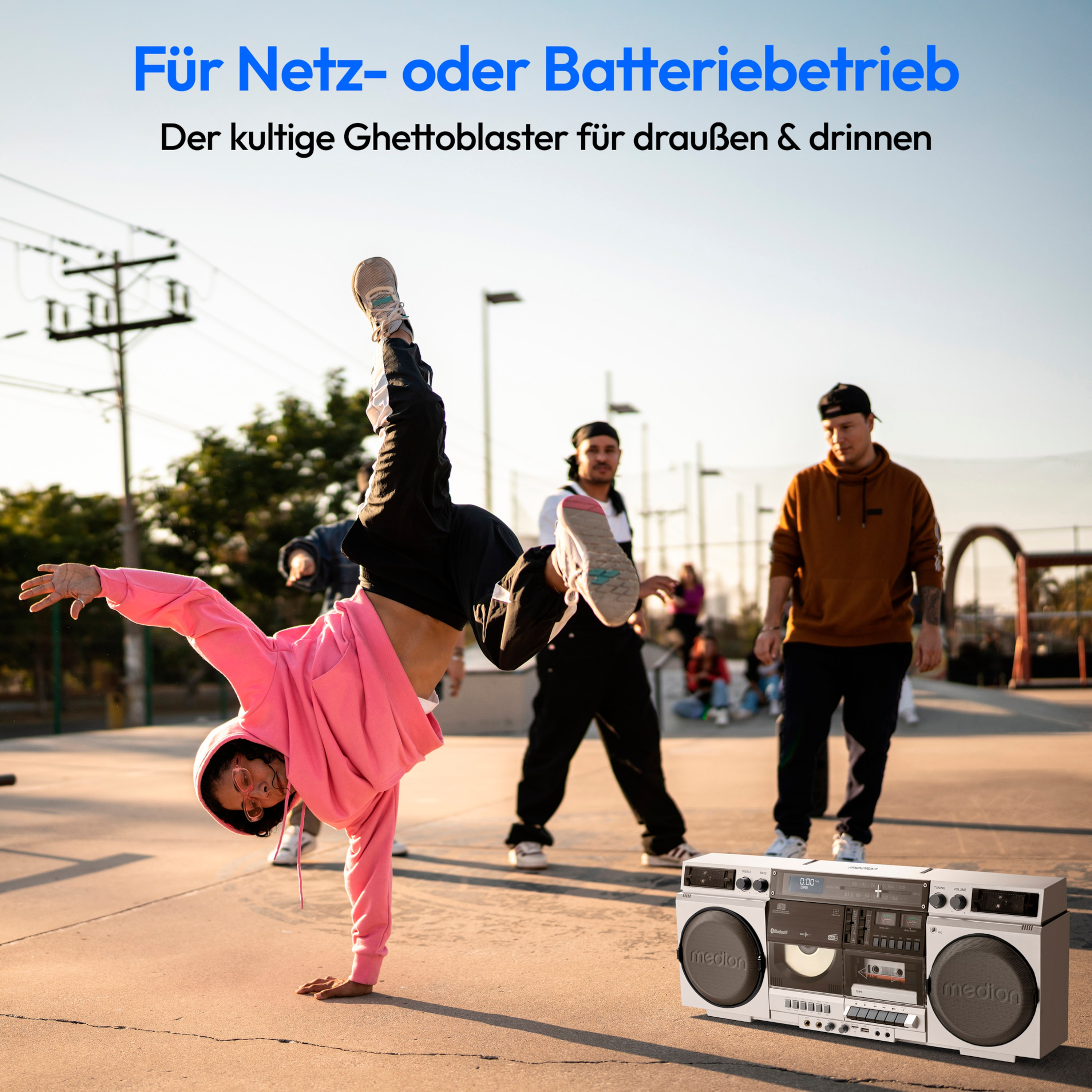 Person macht Handstand in der Nähe einer Boombox mit anderen Personen auf Beton.