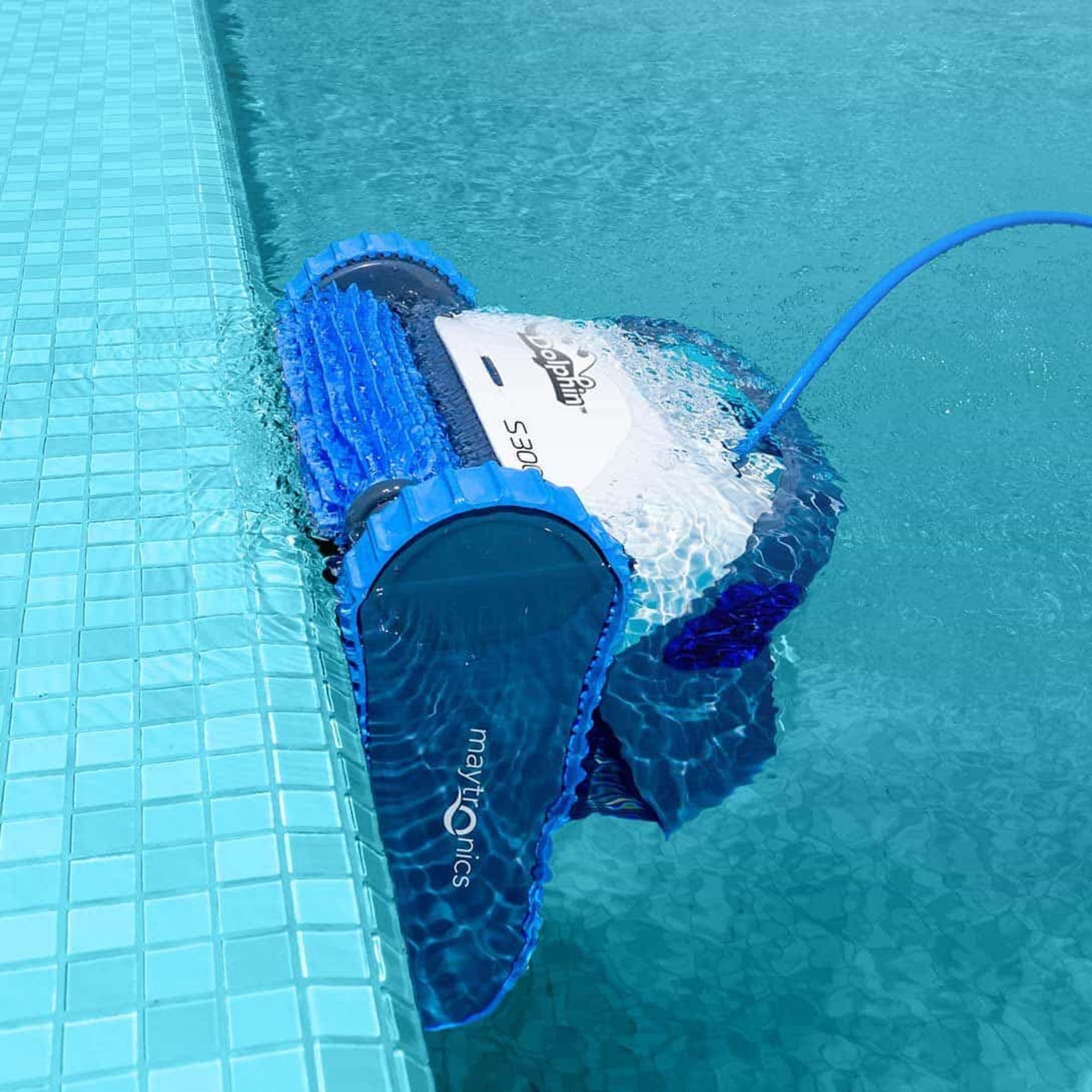 Un limpiafondos robótico azul y blanco en una piscina. Tiene un cepillo azul y está parcialmente sumergido.