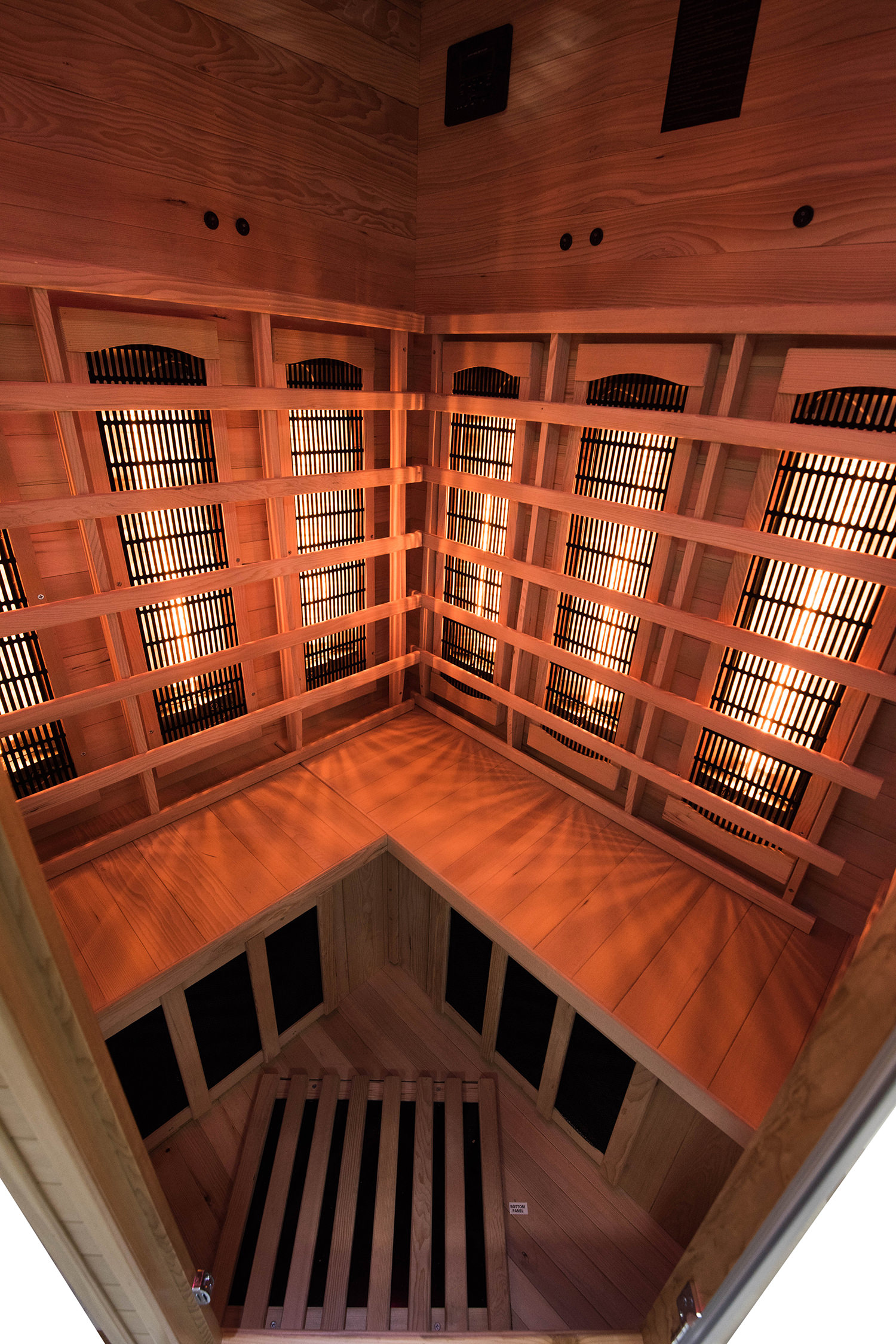 Vista interior de una sauna de madera con múltiples calentadores, iluminada con luz cálida.