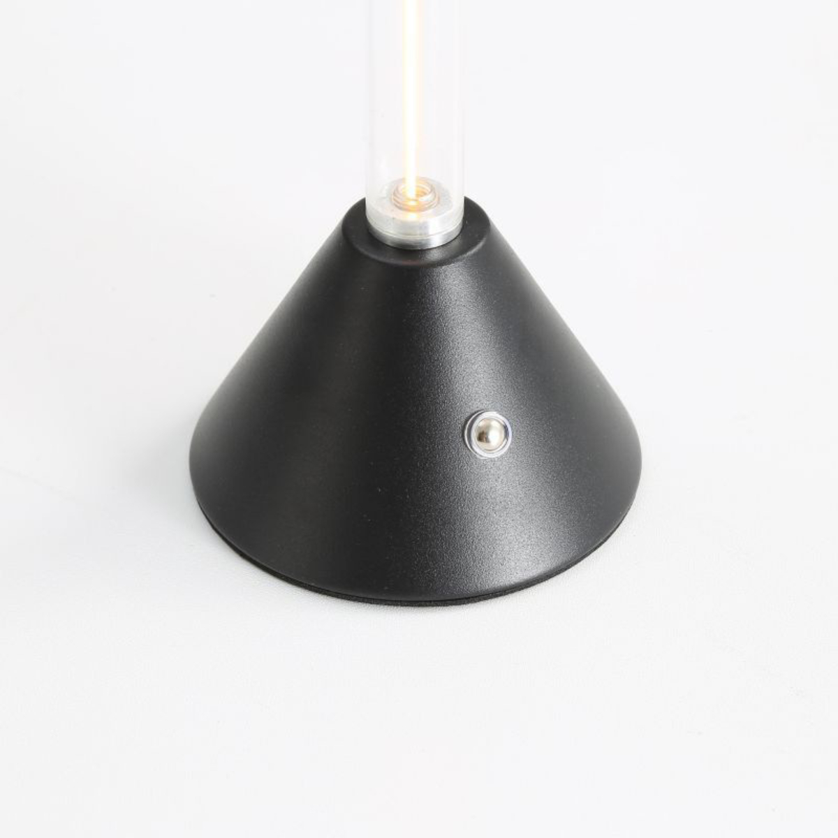 Schwarze Lampe, konischer Sockel, Glasröhre mit gelbem Licht. Weißer Hintergrund.