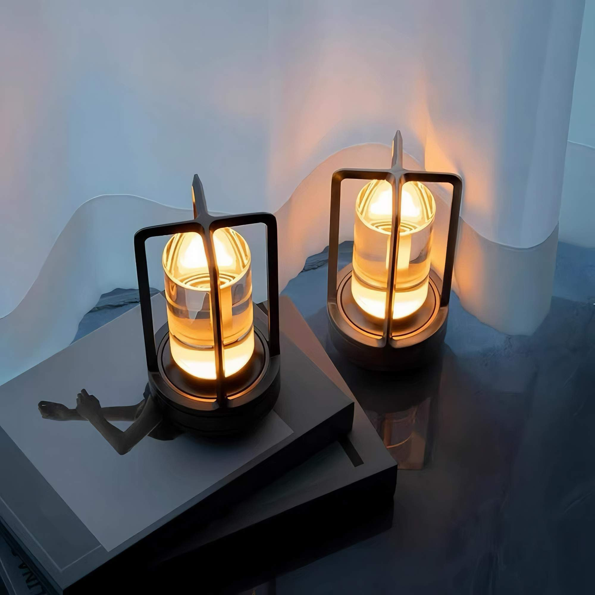 Zwei beleuchtete dekorative Lampen mit Metallrahmen und zylindrischem Glas. Sie stehen auf einer dunklen Oberfläche.