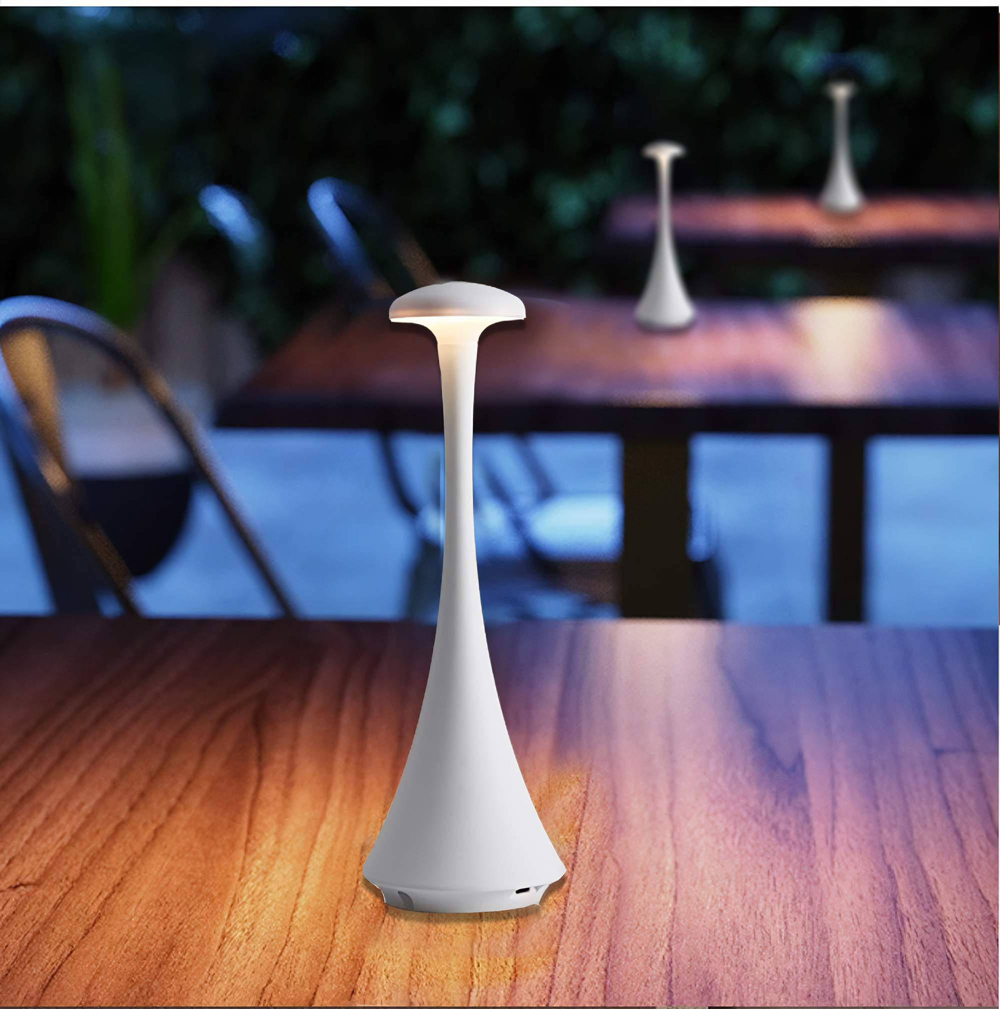 Weiße Tischlampe auf einem Holztisch, mit verschwommenem Hintergrund eines Restaurants.