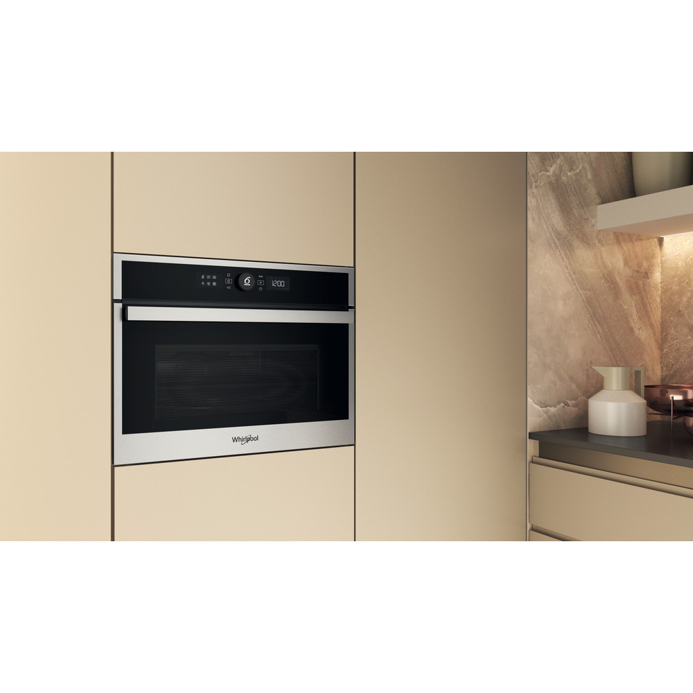 Un horno microondas Whirlpool empotrado en una pared beige. A la derecha un armario.