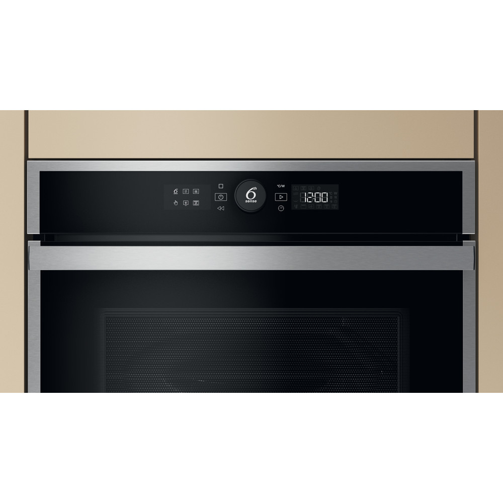 Horno microondas con frontal negro, ribete plateado y pantalla digital. Fondo de pared beige.