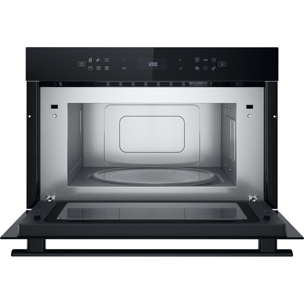 El interior de un horno microondas negro con la puerta abierta, mostrando un plato giratorio de vidrio.
