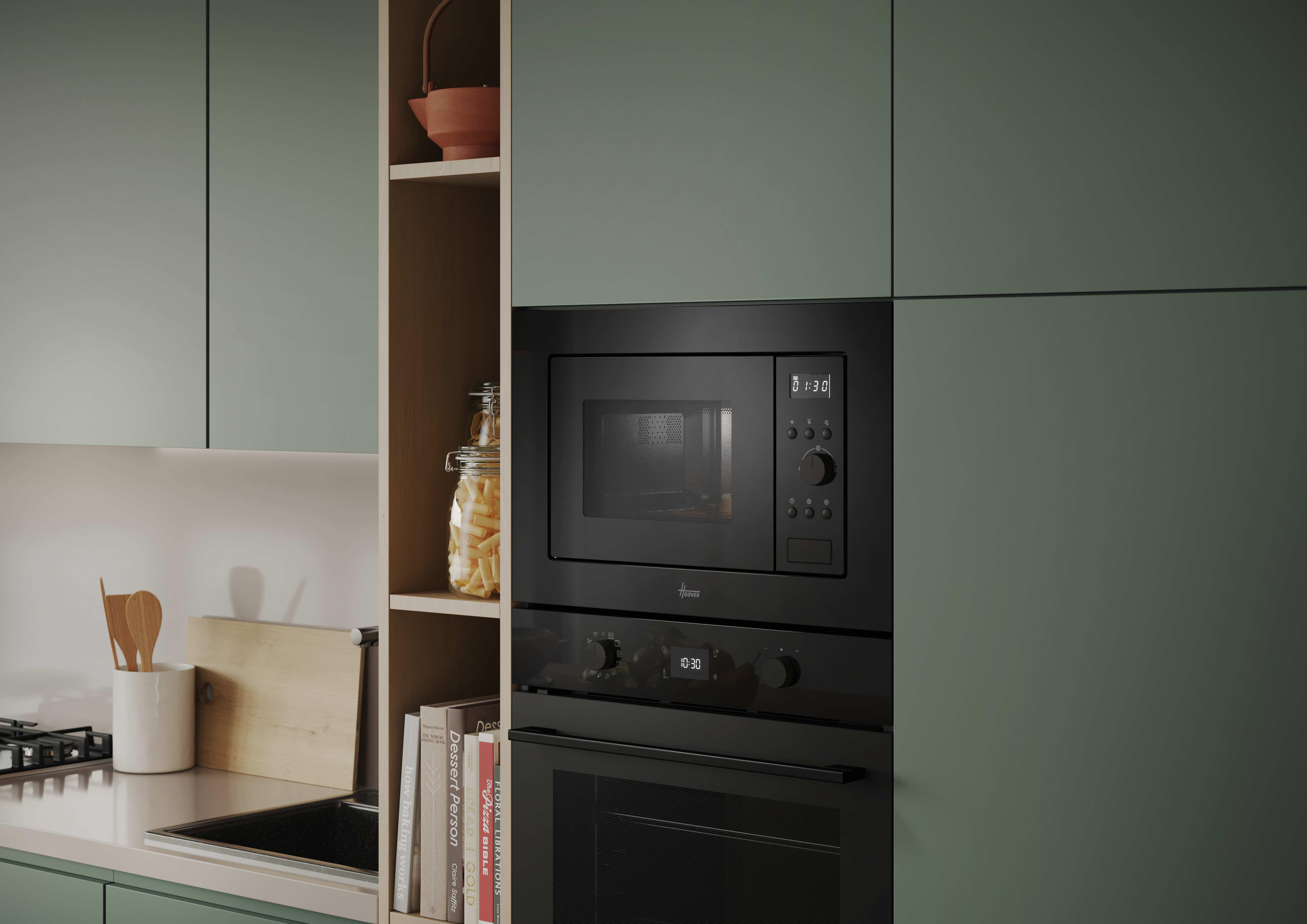 Cocina con gabinetes verdes y un horno negro. Libros y un frasco con pasta son visibles.