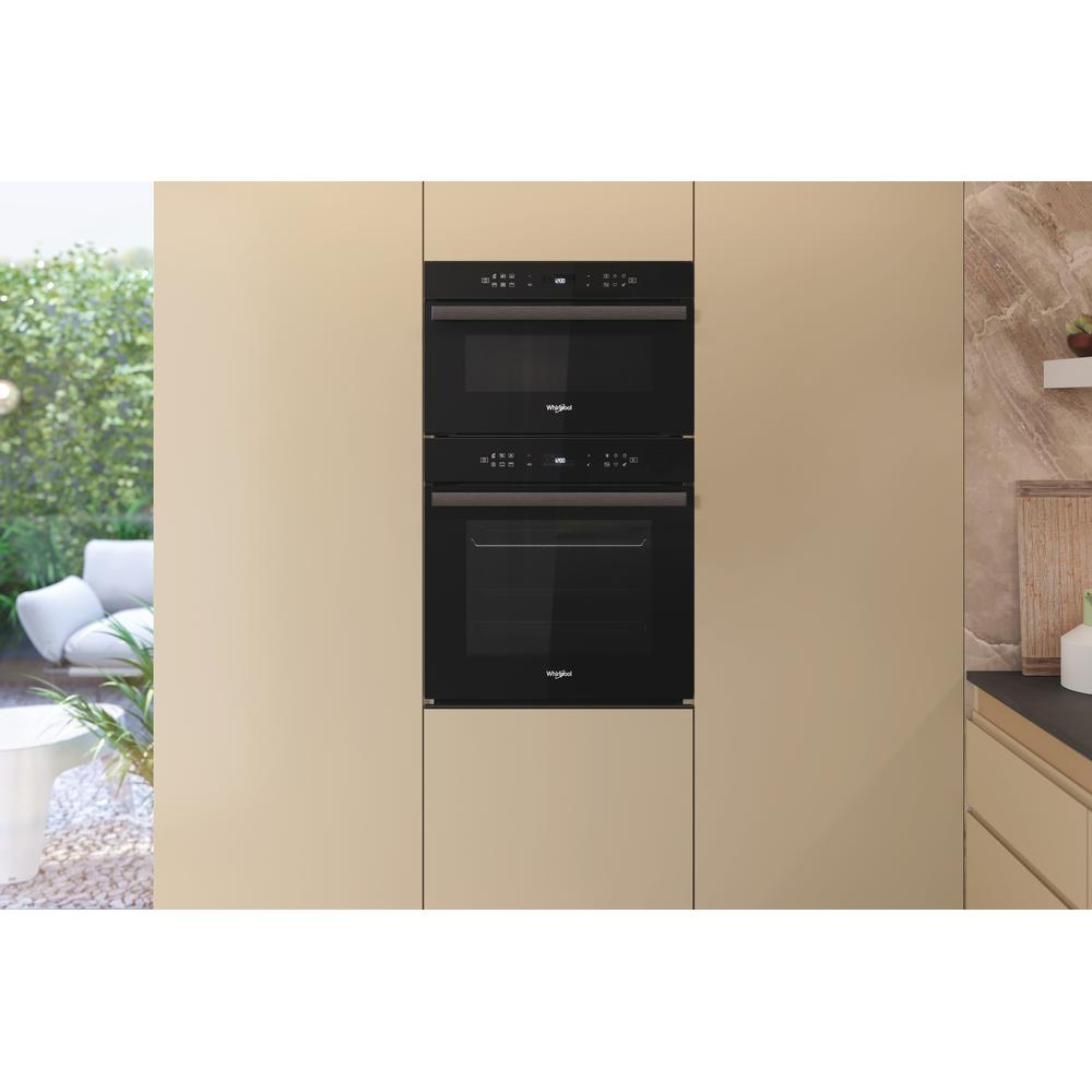 Dwa piekarniki do zabudowy, jeden nad drugim, w beżowej szafce kuchennej. Górny ma wyświetlacz.