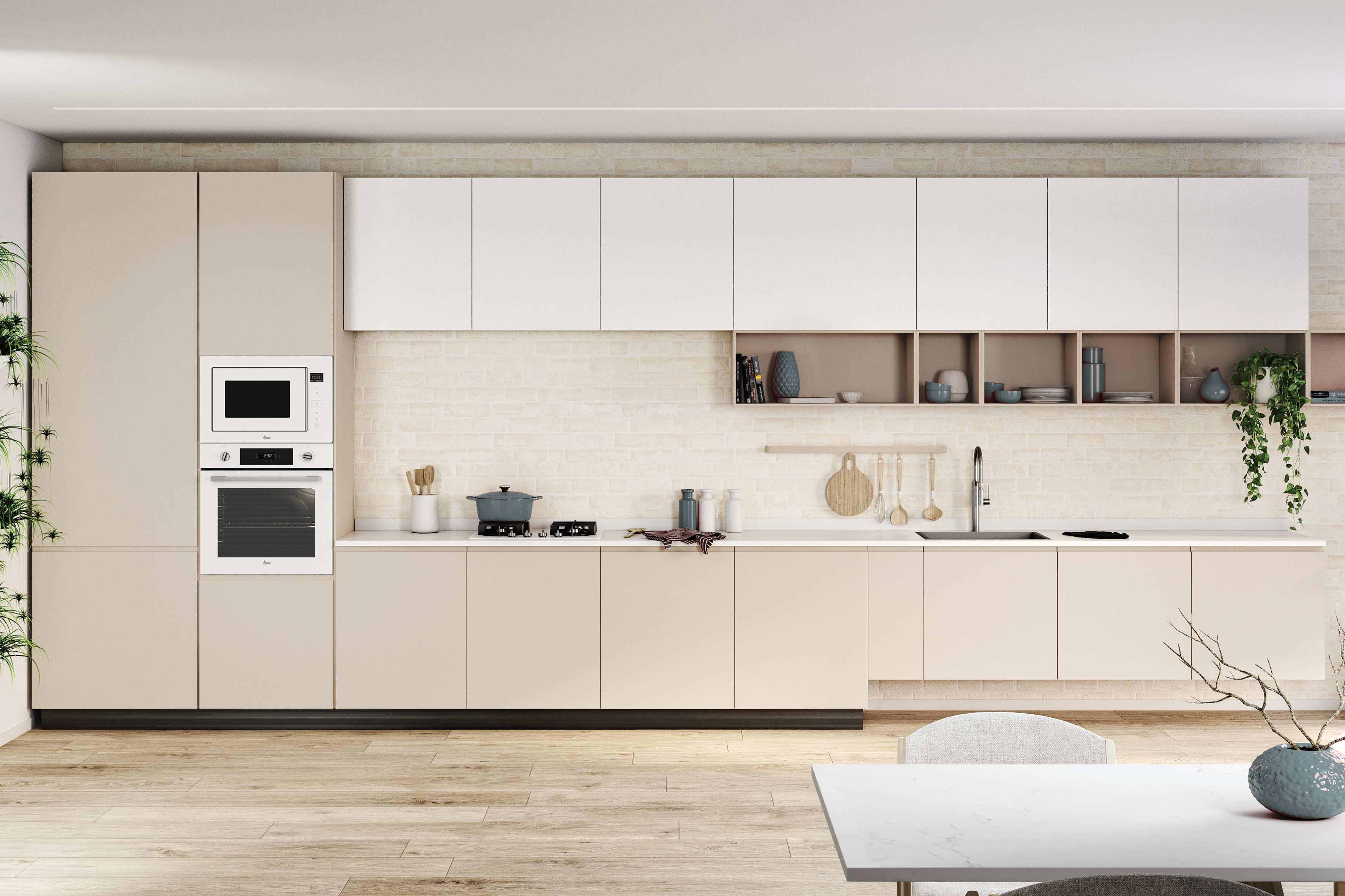 Kuchnia z białymi i beżowymi szafkami, białym blatem oraz kuchenką mikrofalową i piekarnikiem.