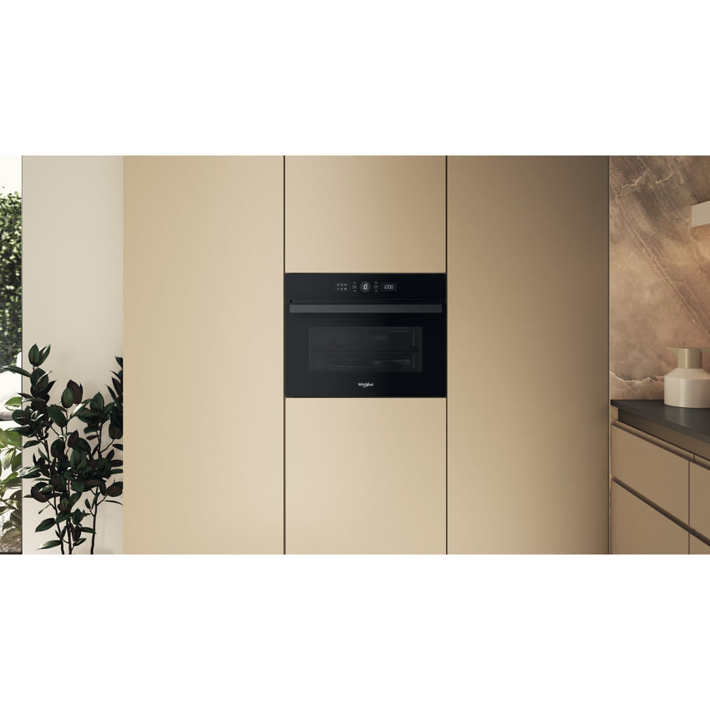 Microondas empotrado en un mueble de cocina. Combinación de colores neutros. Logotipo de Whirlpool visible.