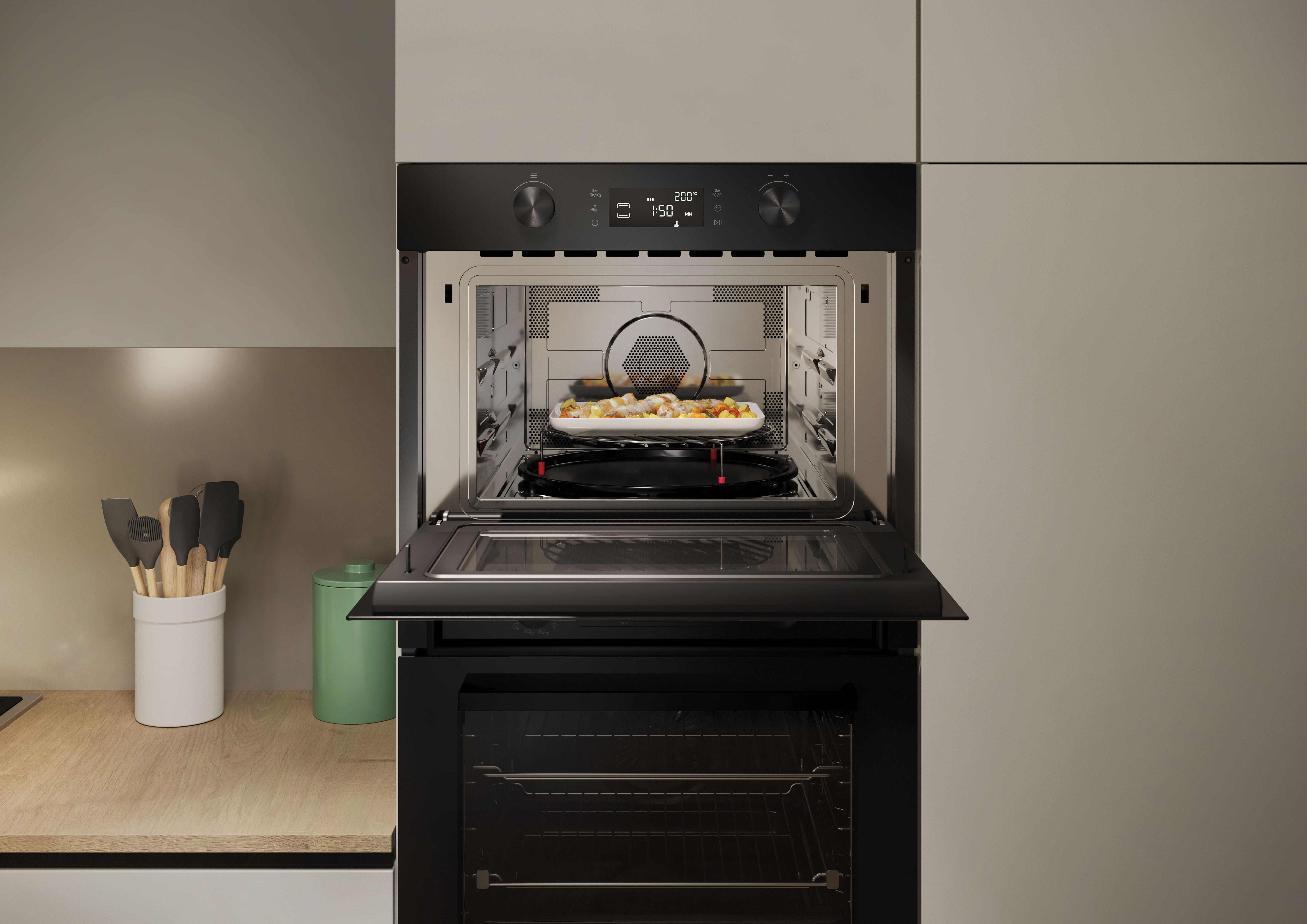 Un forno a microonde in una cucina. La porta è aperta, mostrando il cibo all'interno. Sono visibili utensili e altri oggetti.