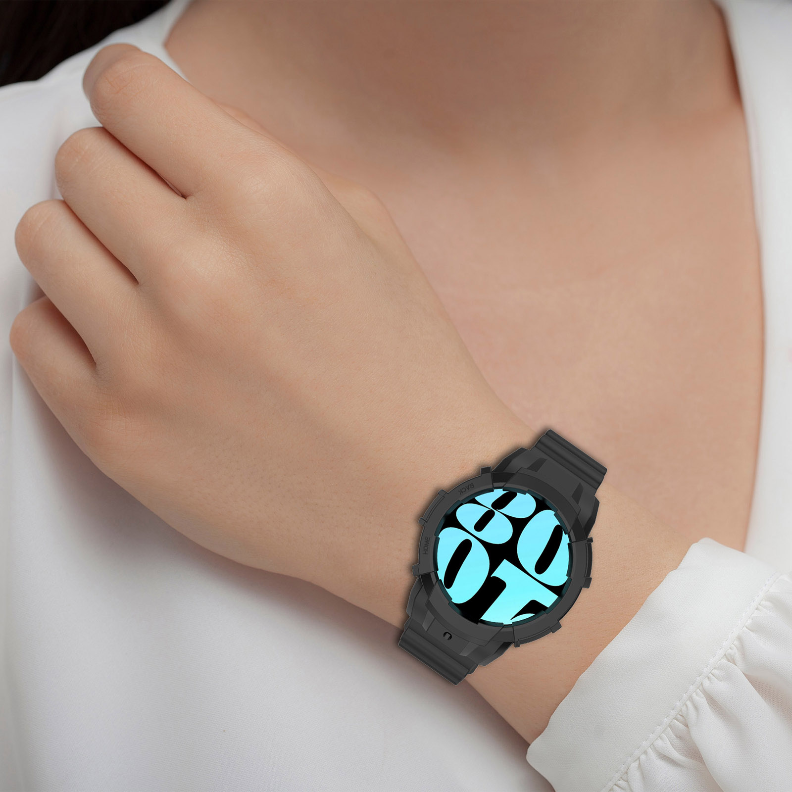 Uno smartwatch nero al polso di una donna, mostra uno schermo blu. La donna indossa una camicia bianca.