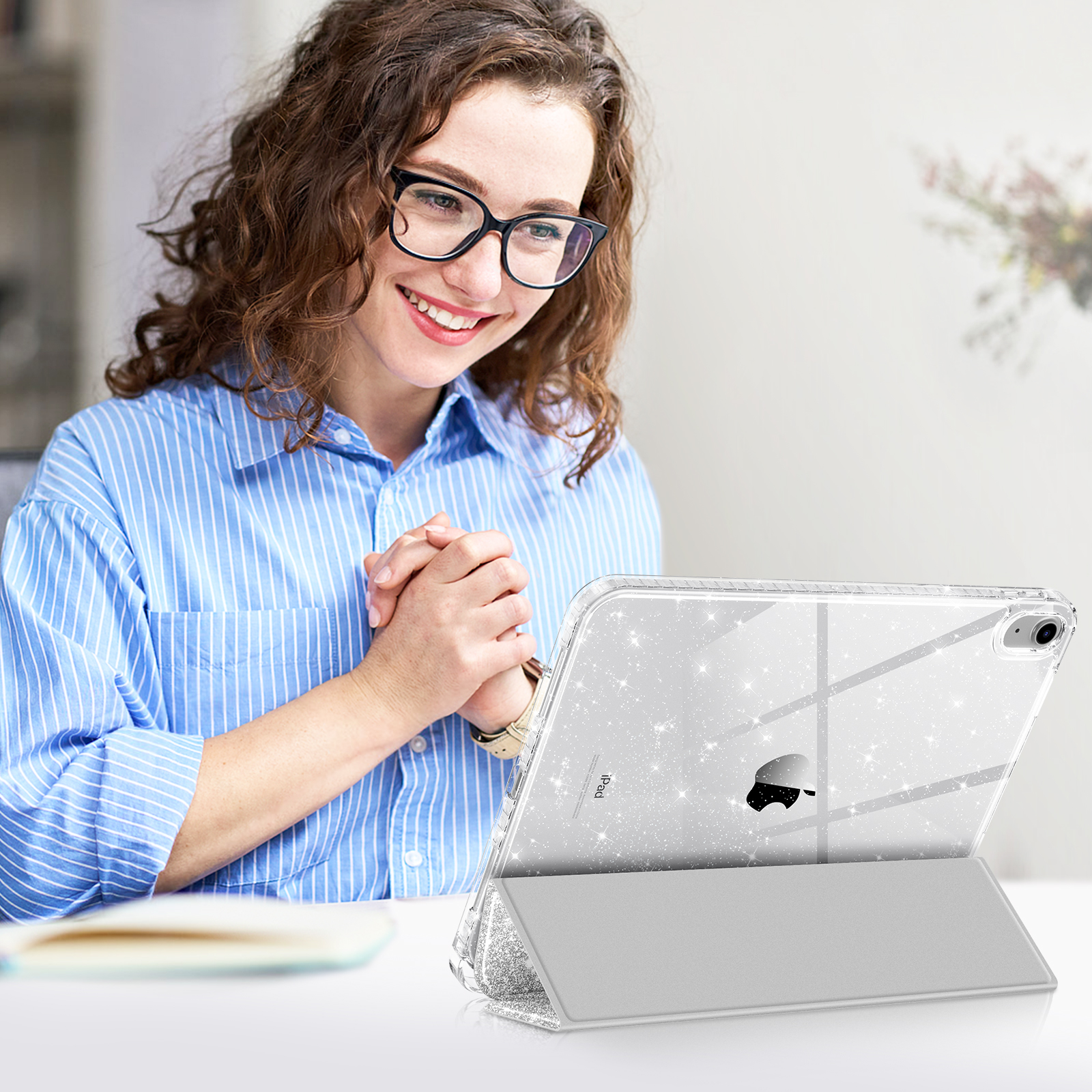 Eine lächelnde Frau mit Brille benutzt ein iPad. Das iPad ist in einer glitzernden Hülle.