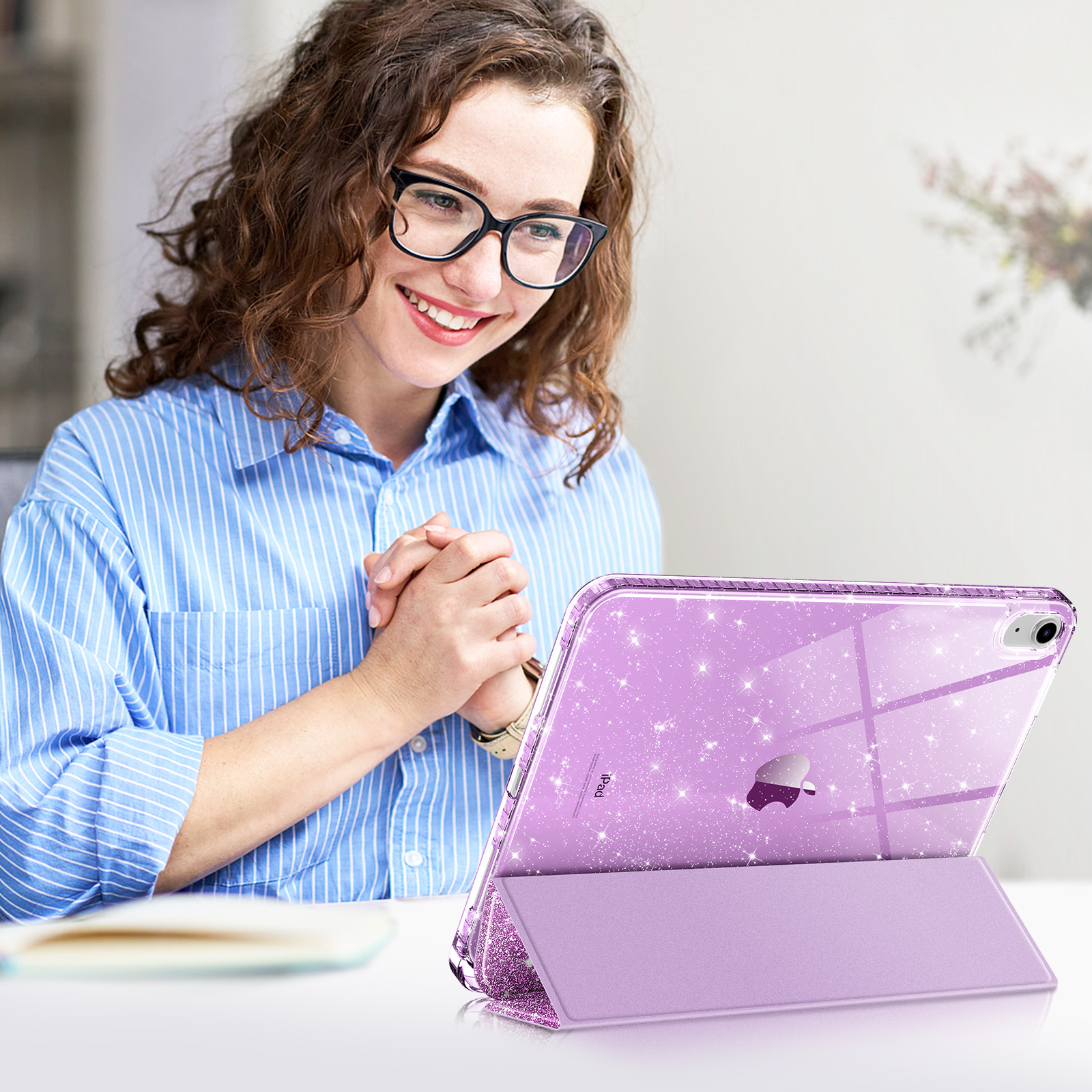 Frau mit Brille betrachtet ein lila glitzerndes Tablet. Das Tablet steht auf einem Ständer.