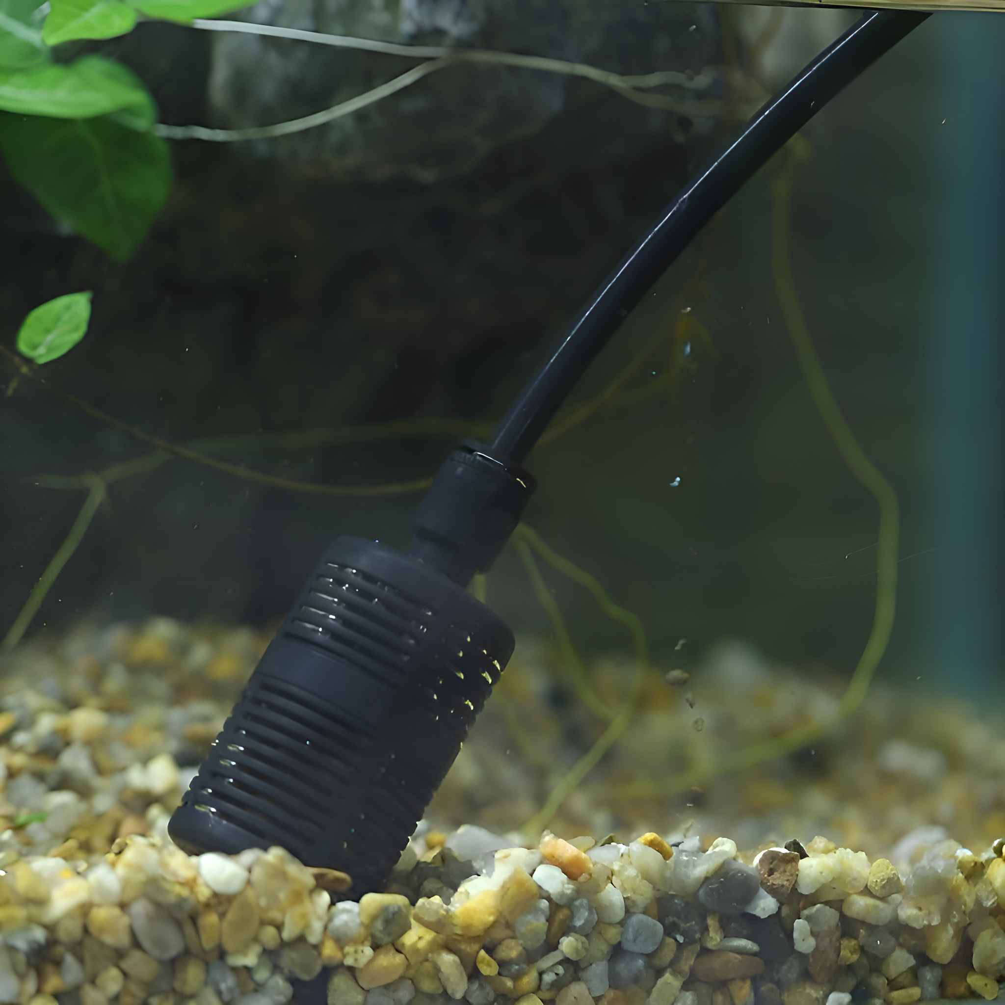 Schwarzer Aquarienfilter, der in Wasser mit Kies und Pflanzen im Hintergrund eingetaucht ist.
