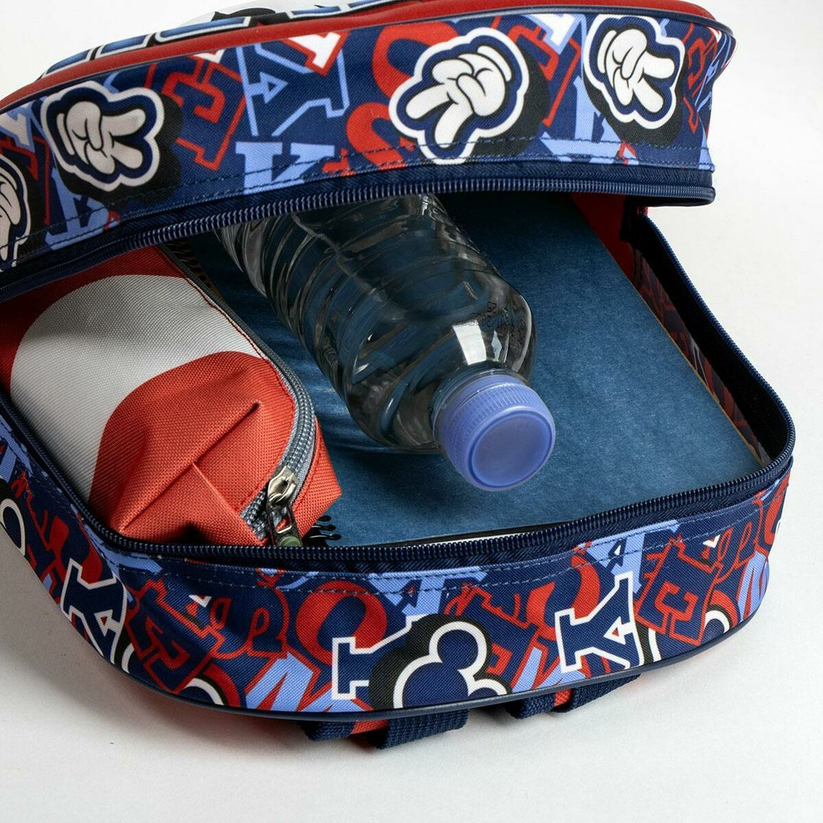 Offener Rucksack mit Wasserflasche, Federmäppchen und Notizbuch im Inneren mit blauem und rotem Design.