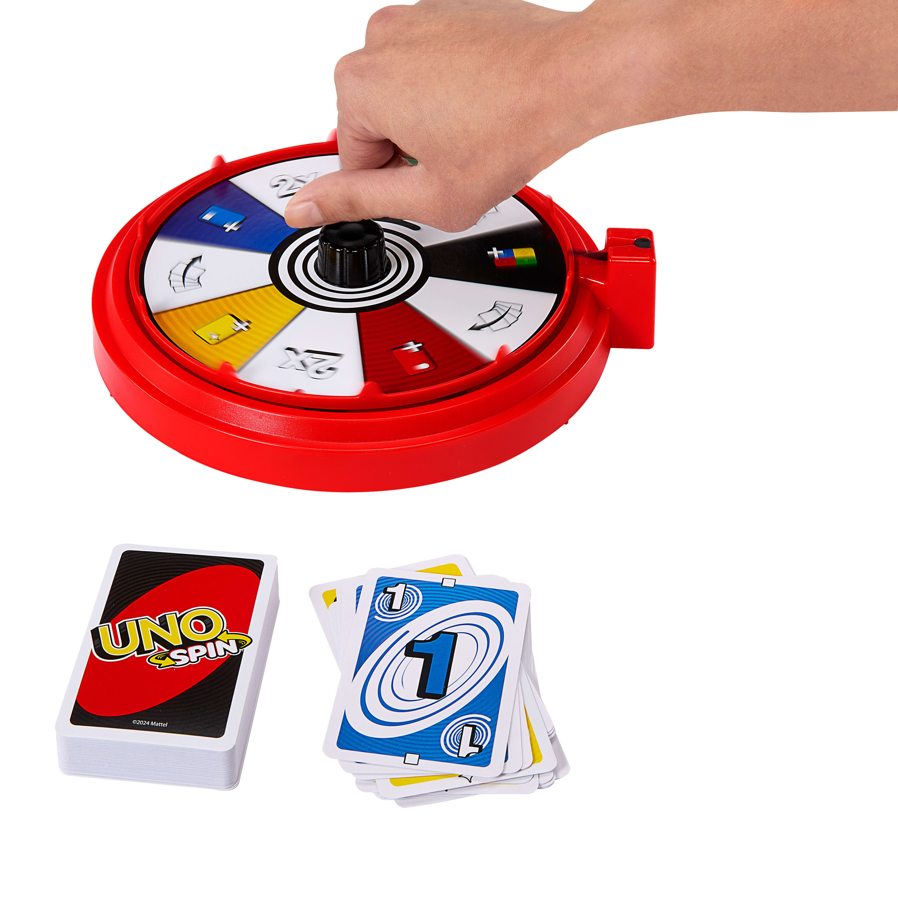 Une main fait tourner la roue du jeu Uno Spin. Il y a des cartes et un jeu de cartes autour.