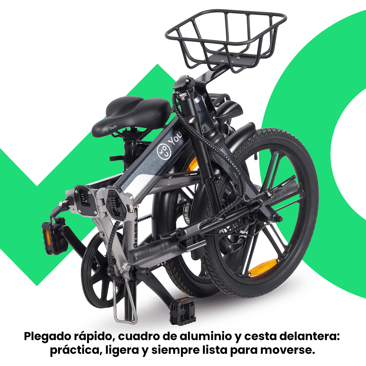 Una bicicleta eléctrica plegada, plateada y negra, con una cesta delantera, sobre un fondo verde.