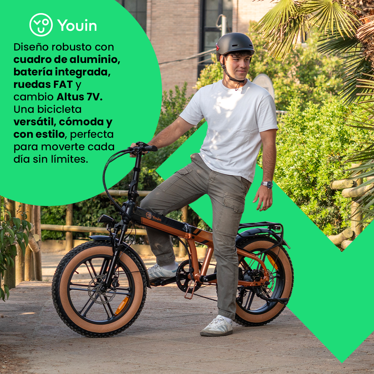 Hombre en bicicleta eléctrica con casco. La bici tiene cuadro marrón, neumáticos gruesos y está en un parque.