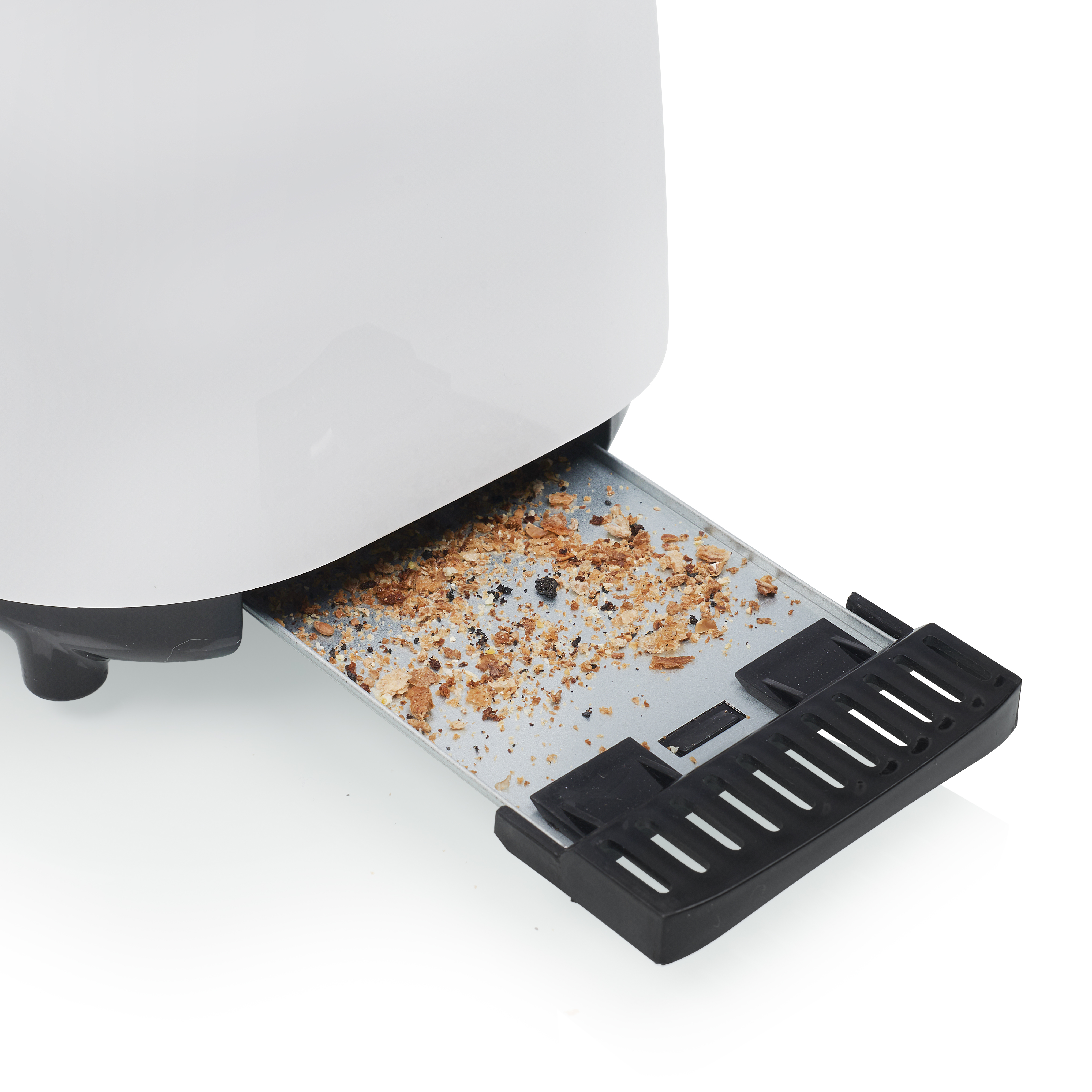 Primer plano de una bandeja de migas de tostadora extraída, llena de migas.