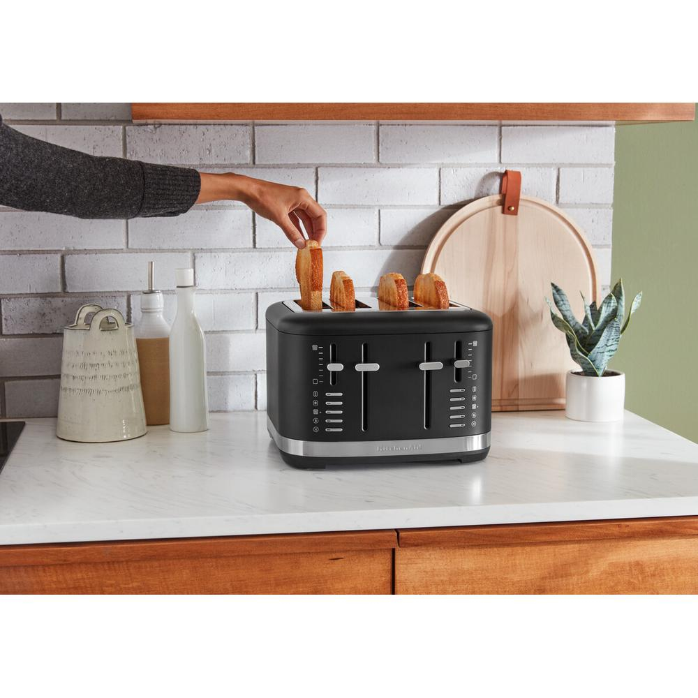 Osoba opieka chleb w czarnym tosterze KitchenAid na marmurowym blacie.