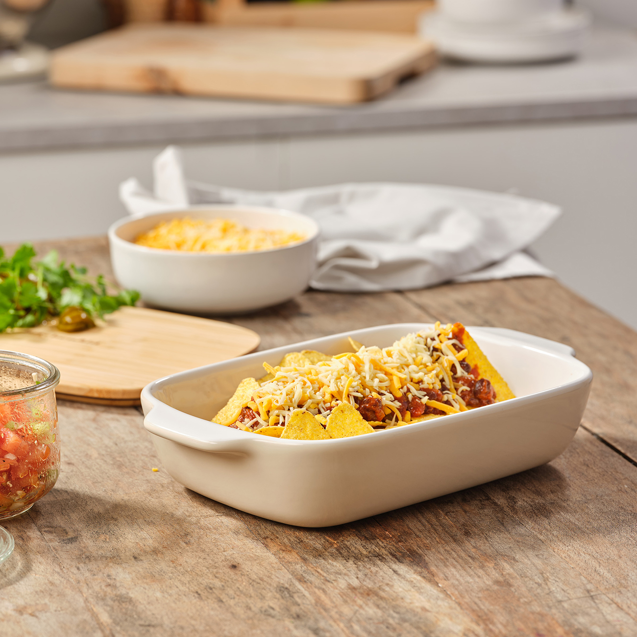 Gericht mit Nachos mit Käse und Fleisch. Zutaten umfassen eine Schüssel Käse und ein Holzschneidebrett.