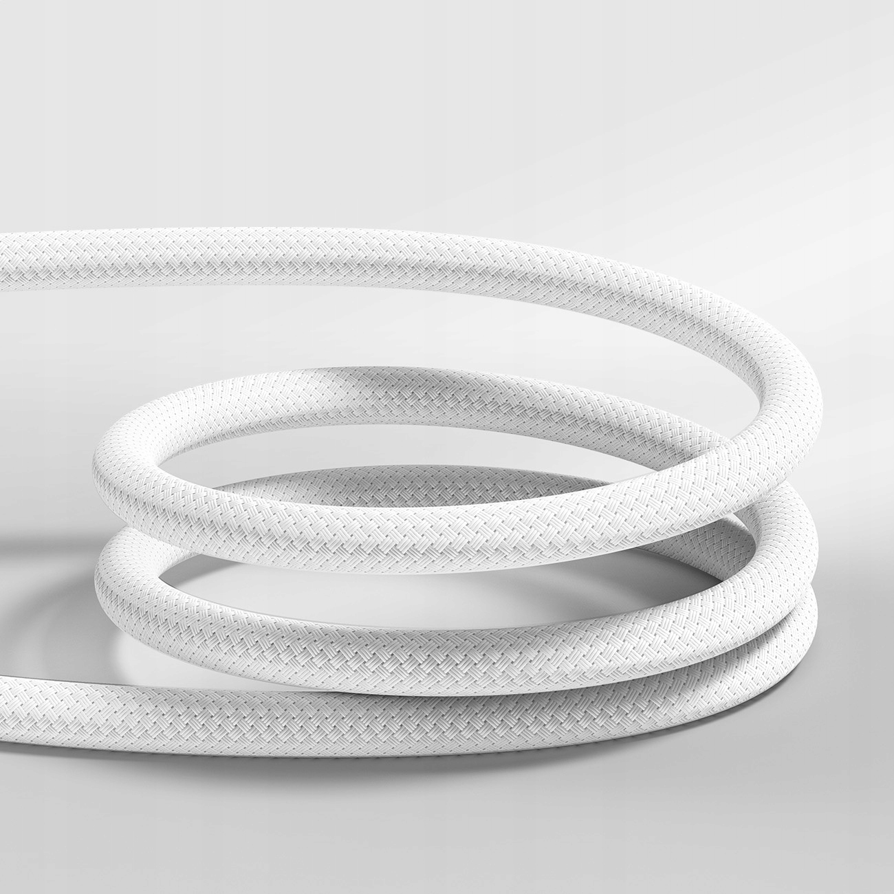 Ein weißes, gewendeltes Kabel mit strukturierter Oberfläche liegt auf hellgrauer Oberfläche.