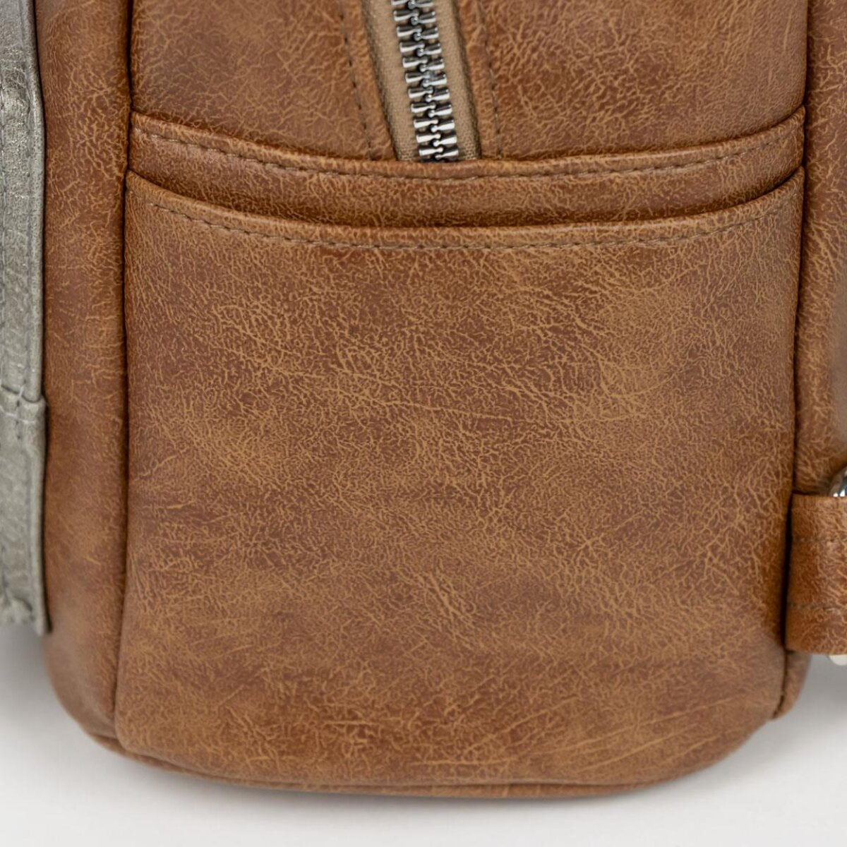 Primer plano de un bolsillo de mochila de cuero marrón con cremallera.