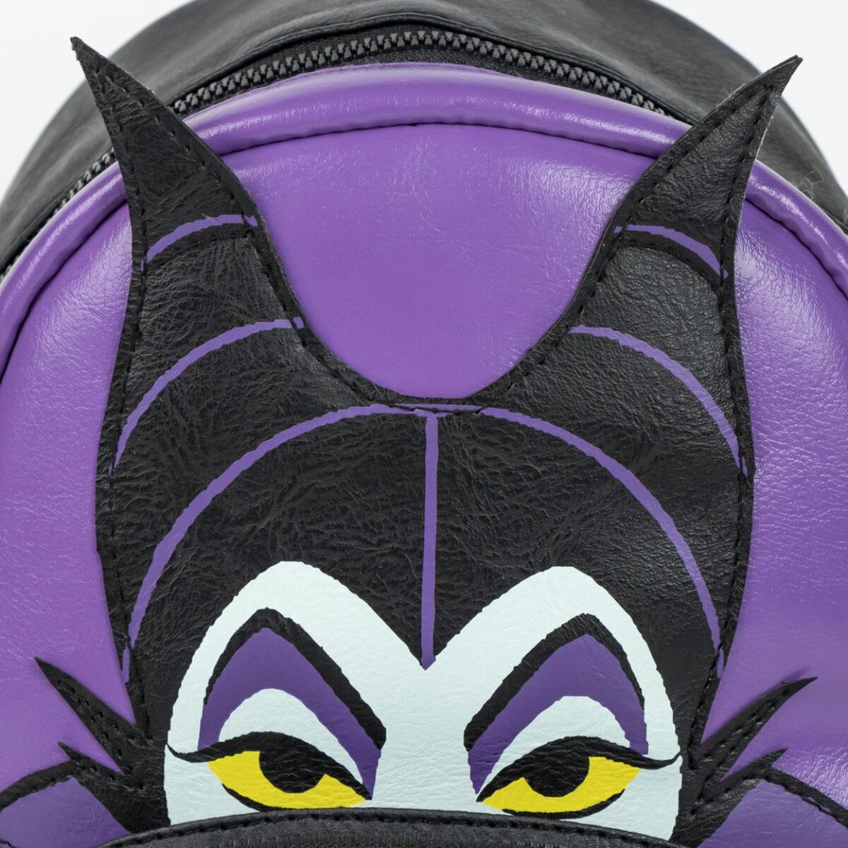 Primer plano de la mochila de Maléfica con cuernos, cara y ojos amarillos sobre púrpura.