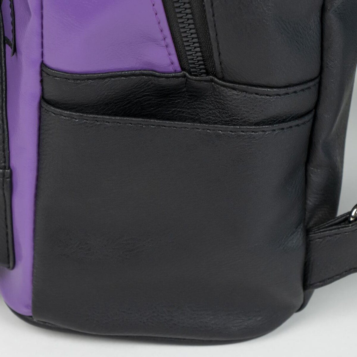 Mochila negra y morada con un bolsillo. Fondo blanco.