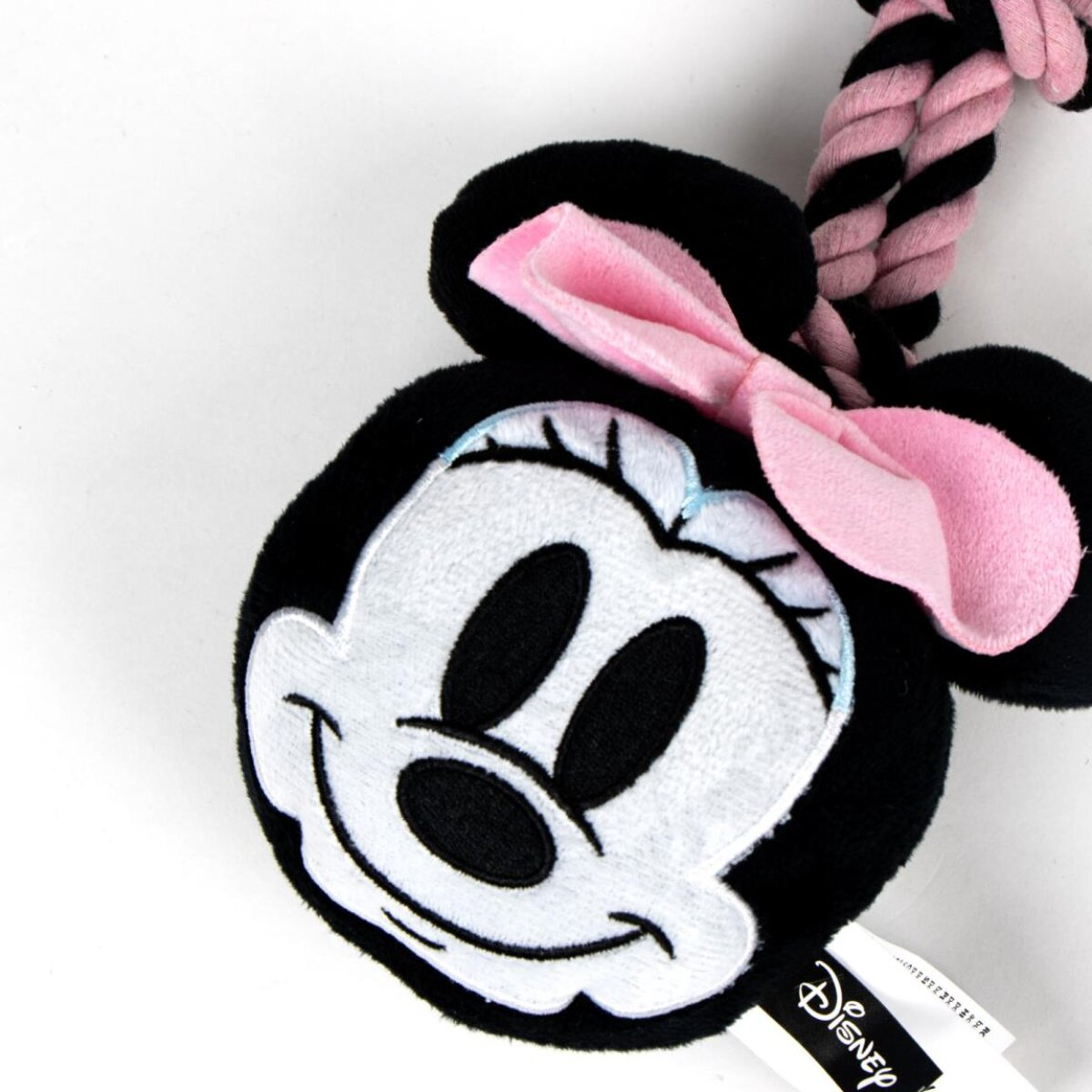 Minnie Mouse Plüschtier mit rosa Schleife, schwarzen Ohren und Seil. Auf weißer Oberfläche.
