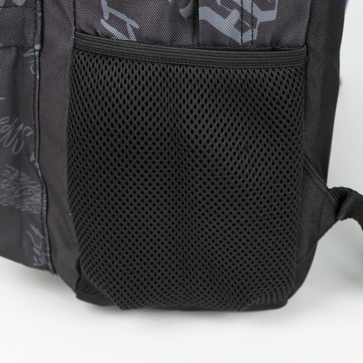 Una mochila negra con un bolsillo lateral de malla. El lateral de la bolsa tiene un patrón de formas grises.