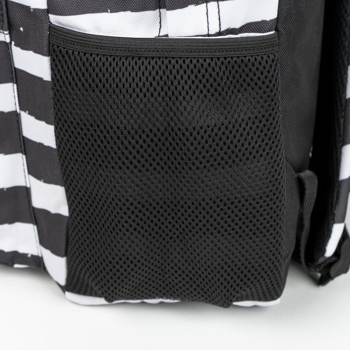 Una mochila a rayas blancas y negras con un bolsillo lateral de malla. La bolsa tiene rayas blancas.