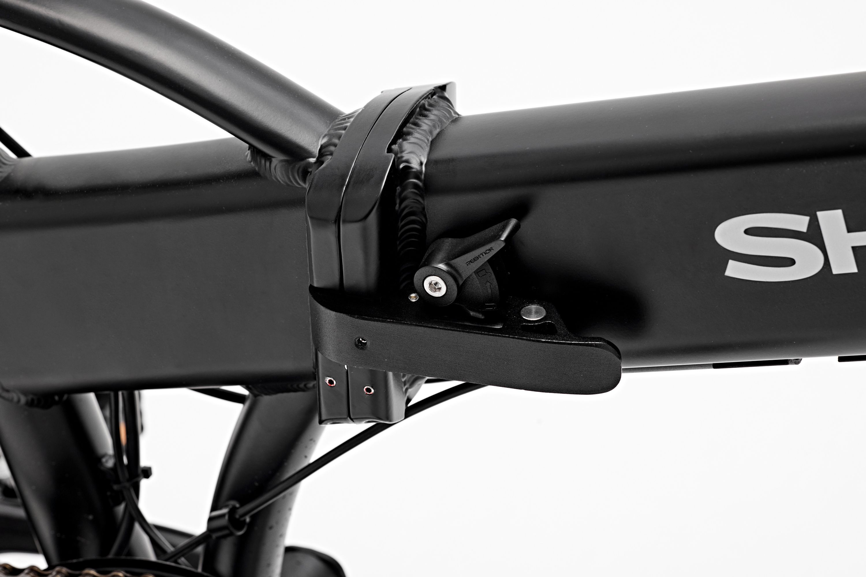 Nahaufnahme des Klappmechanismus an einem schwarzen Fahrrad. Das Wort SHARP ist auf dem Rahmen sichtbar.